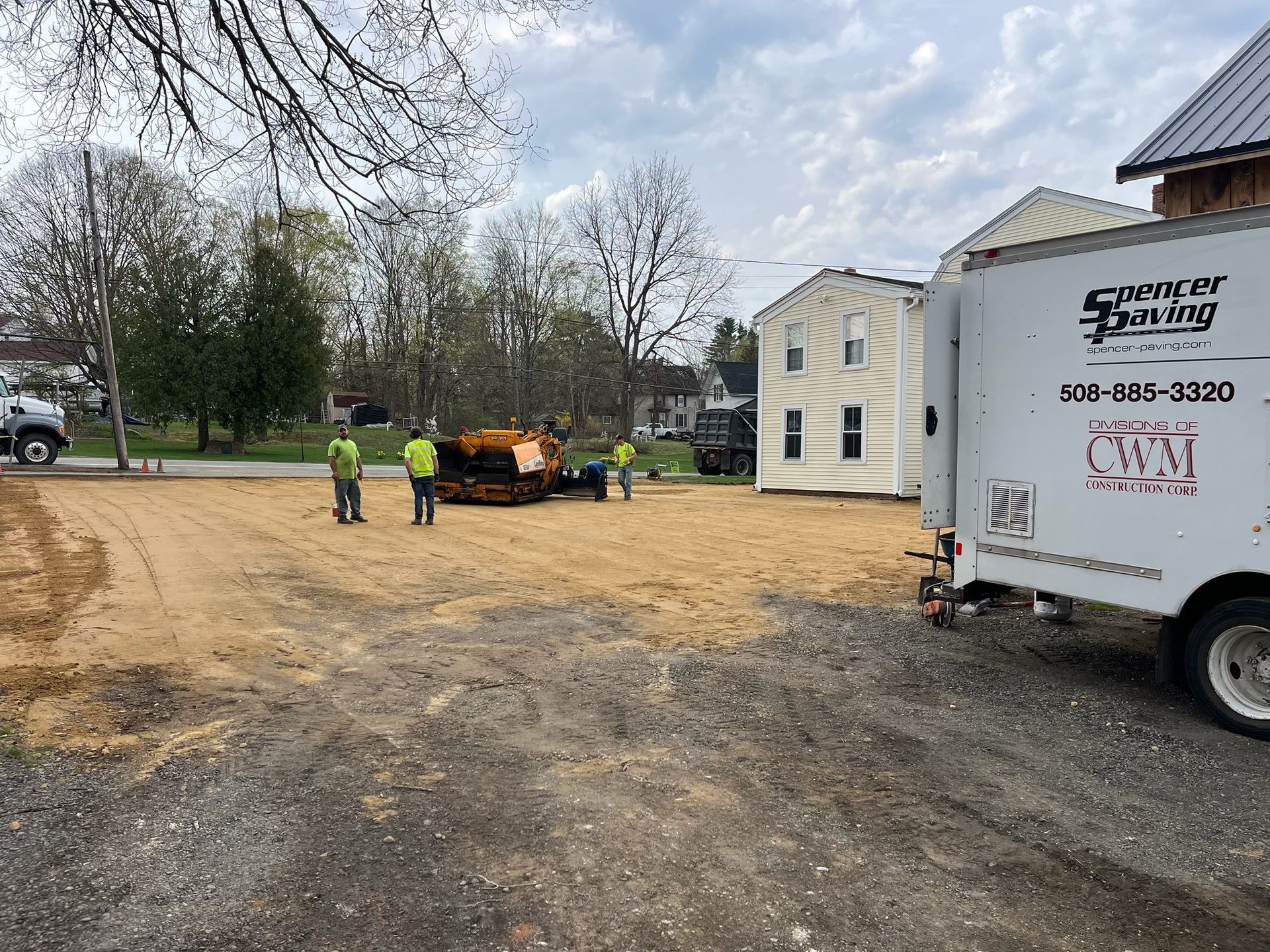 A group of people are standing in a dirt lot next to a truck.