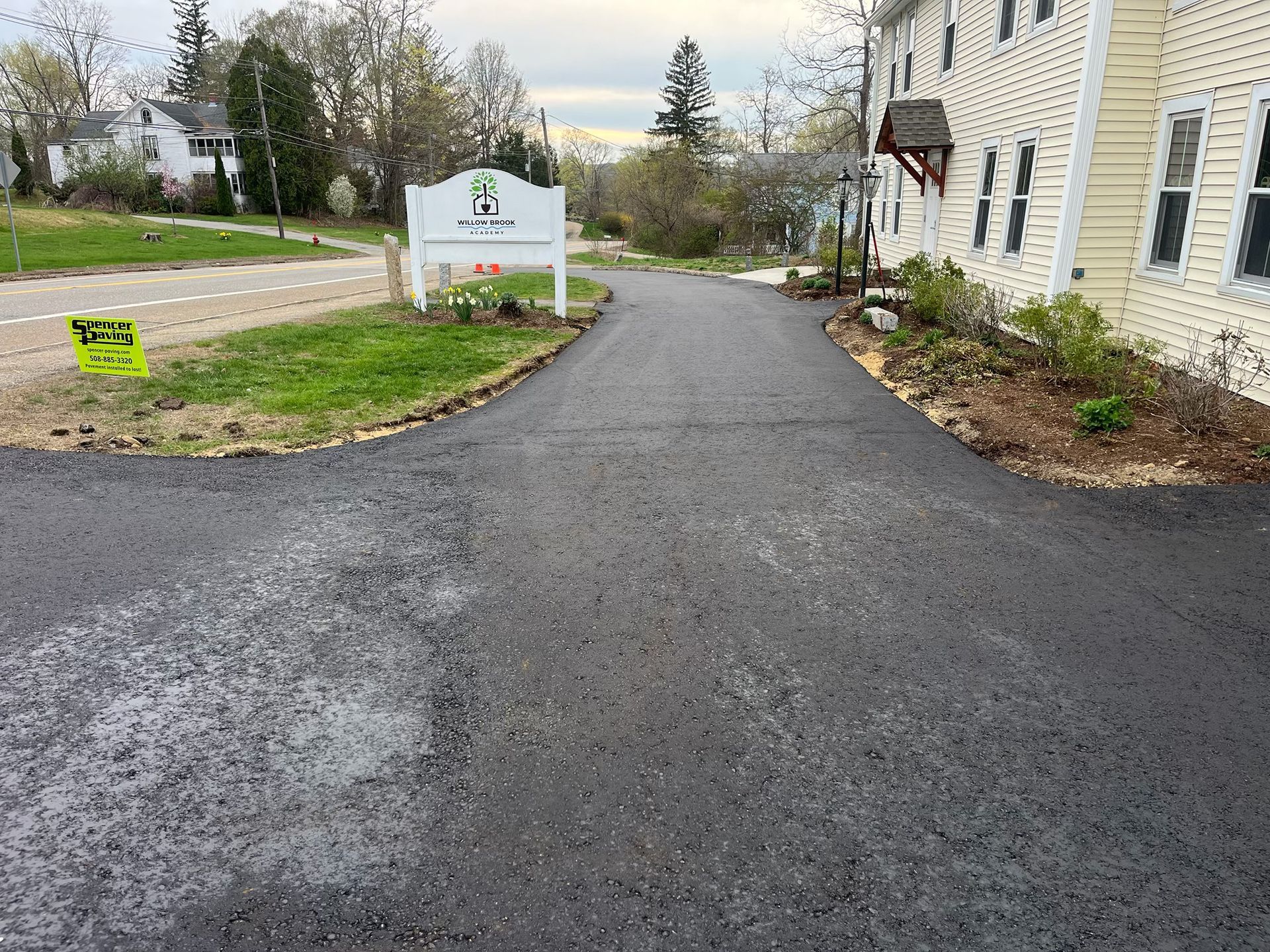A driveway leading to a building with a sign on the side of it.
