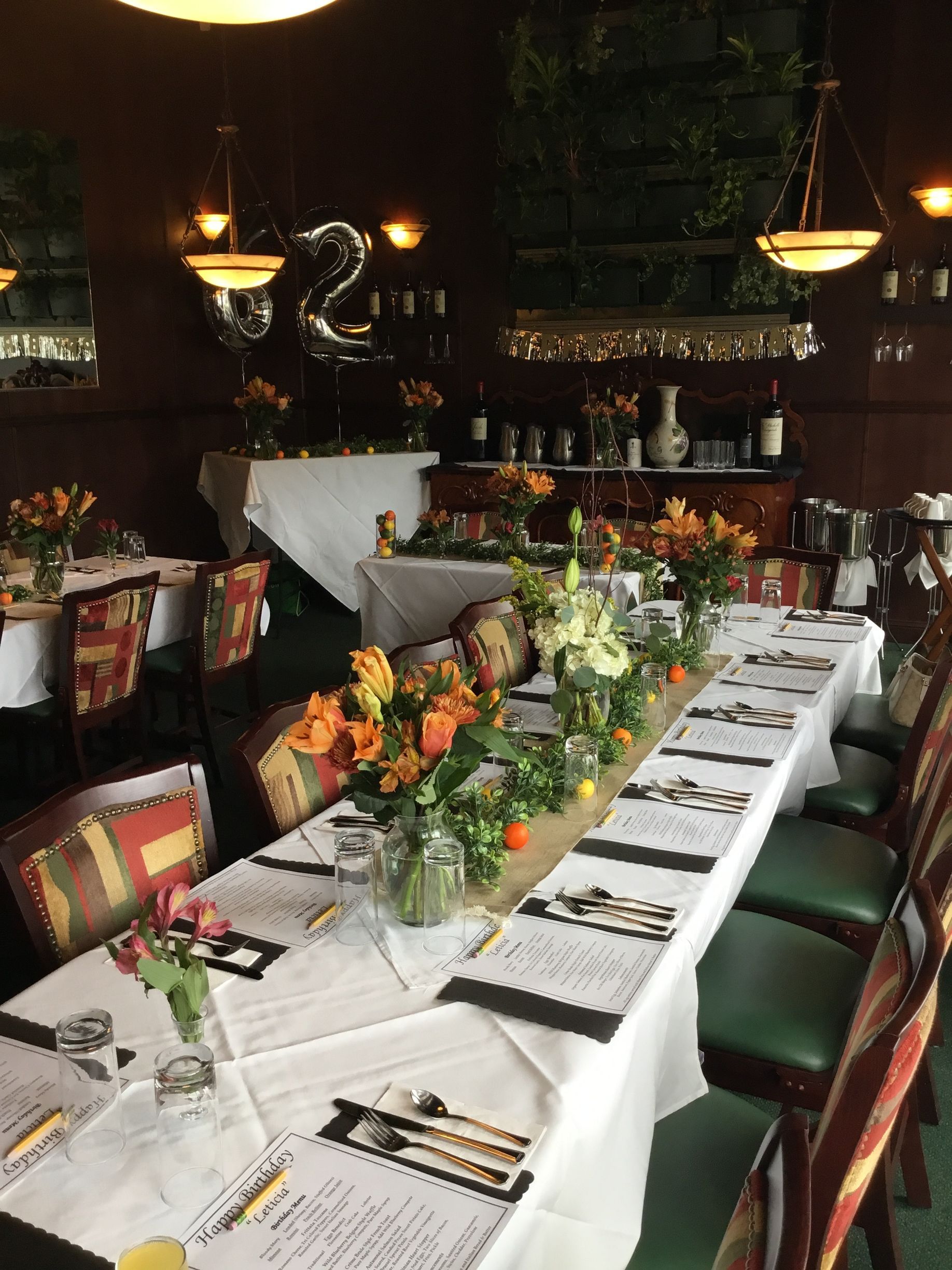 Elegant dining room with long white-clothed table, floral centerpieces, and warm candlelit chandeliers
