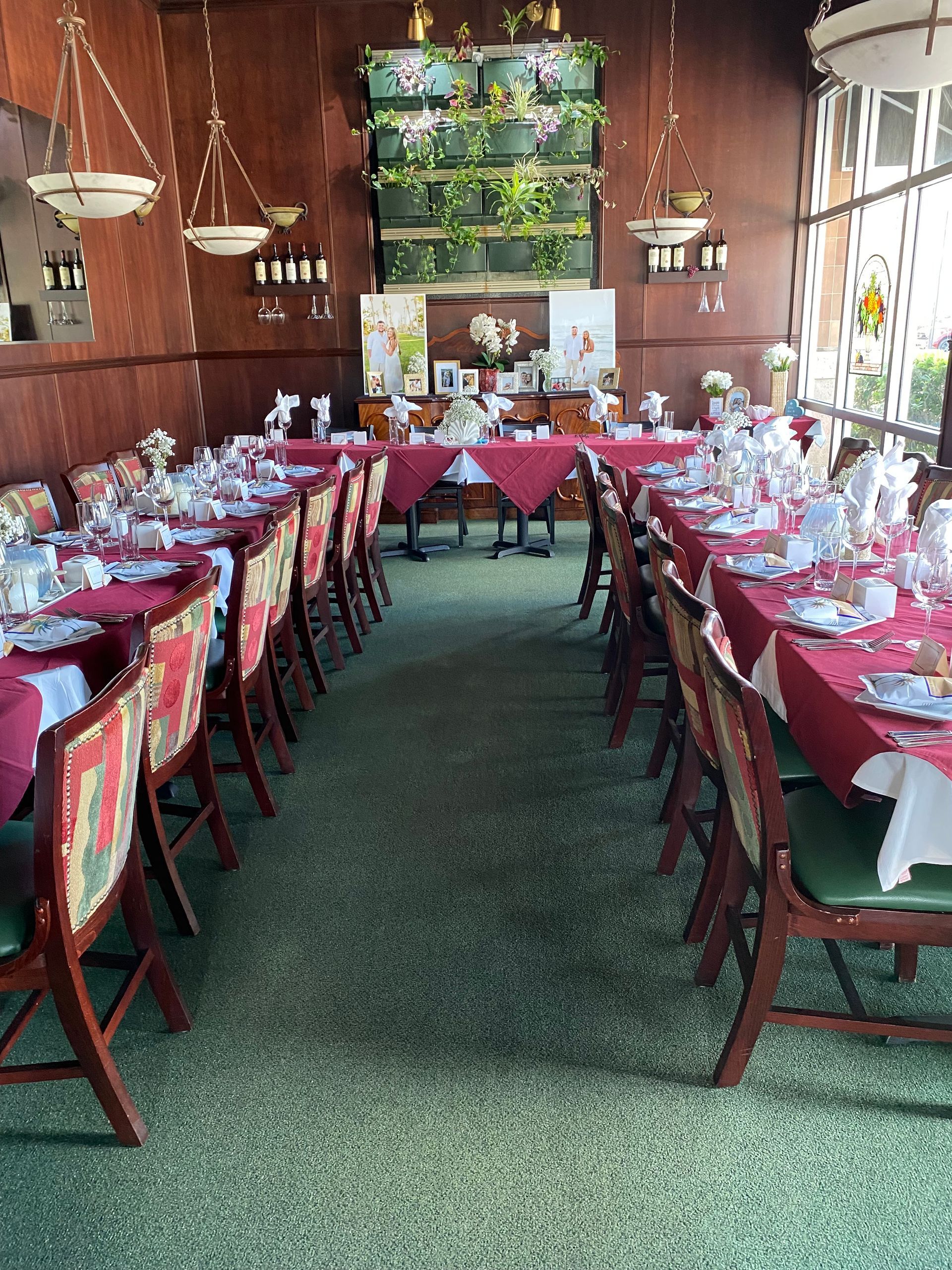 Long dining table set with red tablecloths and flowers in a rustic room with wooden walls