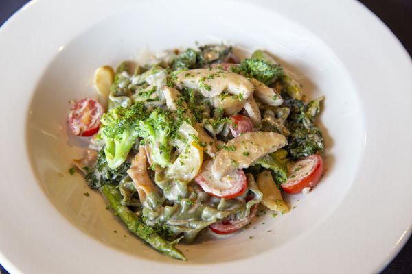 Pasta dish with vegetables and tomatoes in a white bowl.