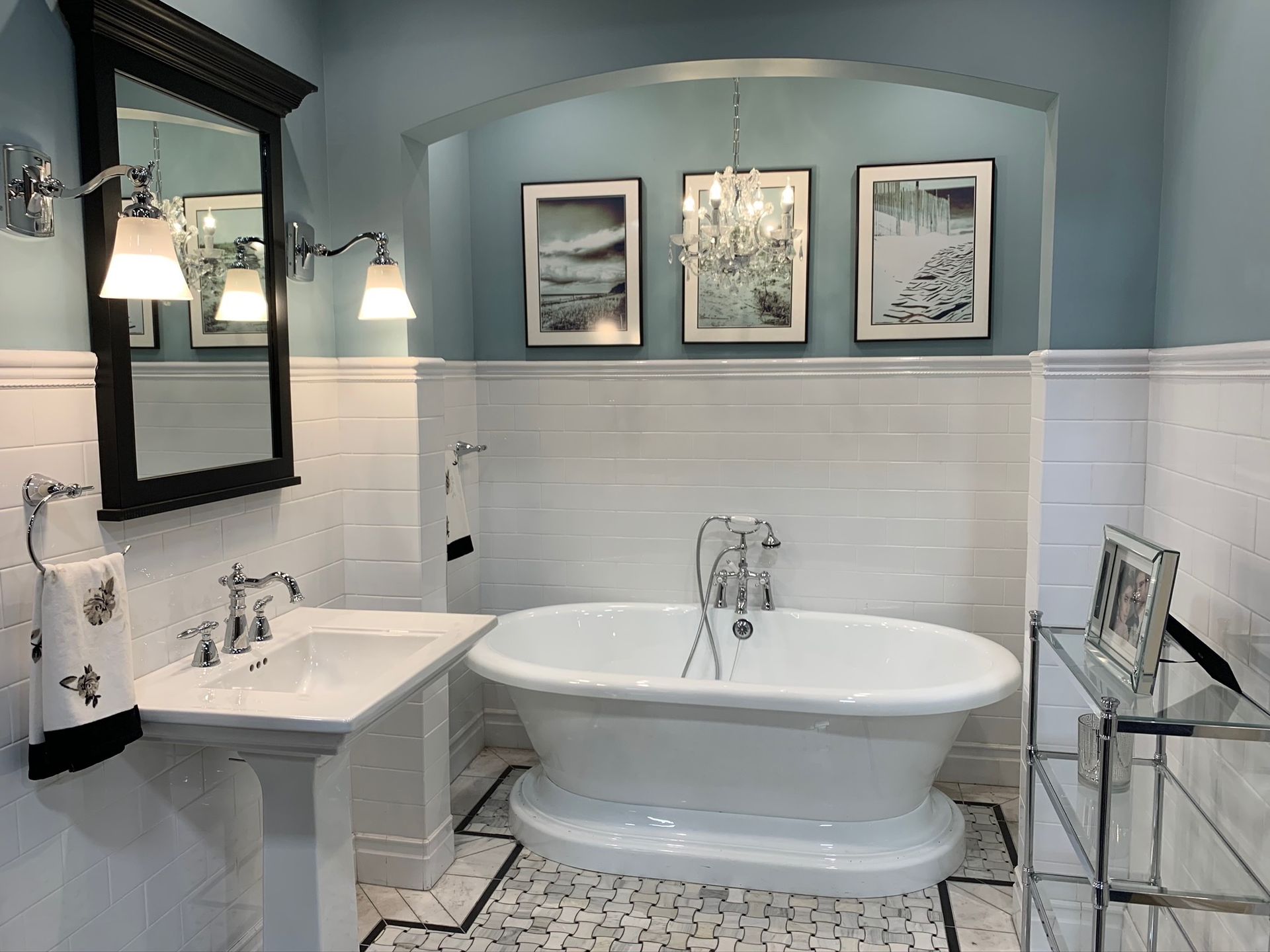 Bathroom with pedestal sink, clawfoot tub, and framed artwork, light blue walls.