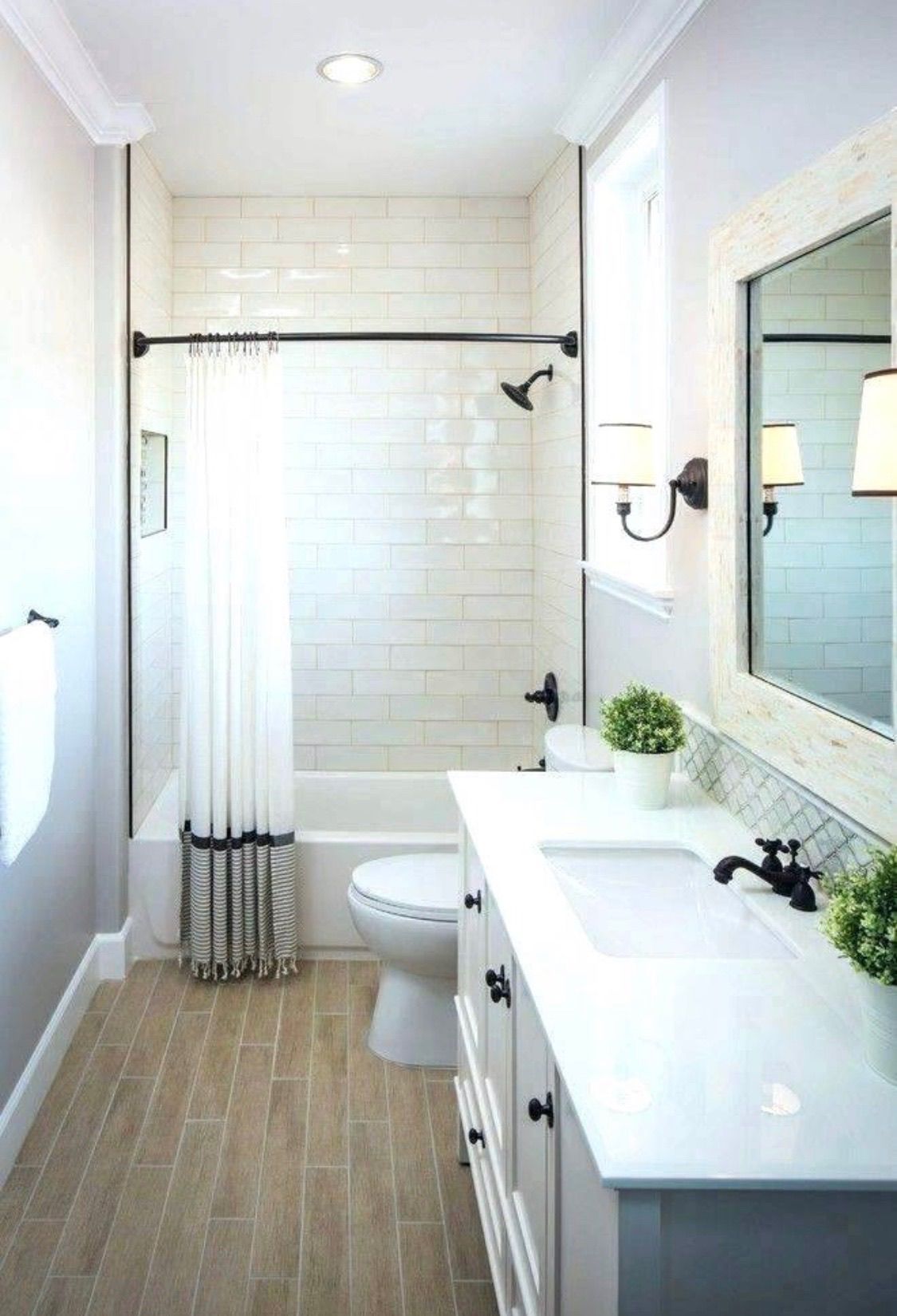 Bright white bathroom with subway tile shower, white vanity, and light wood-look floor.
