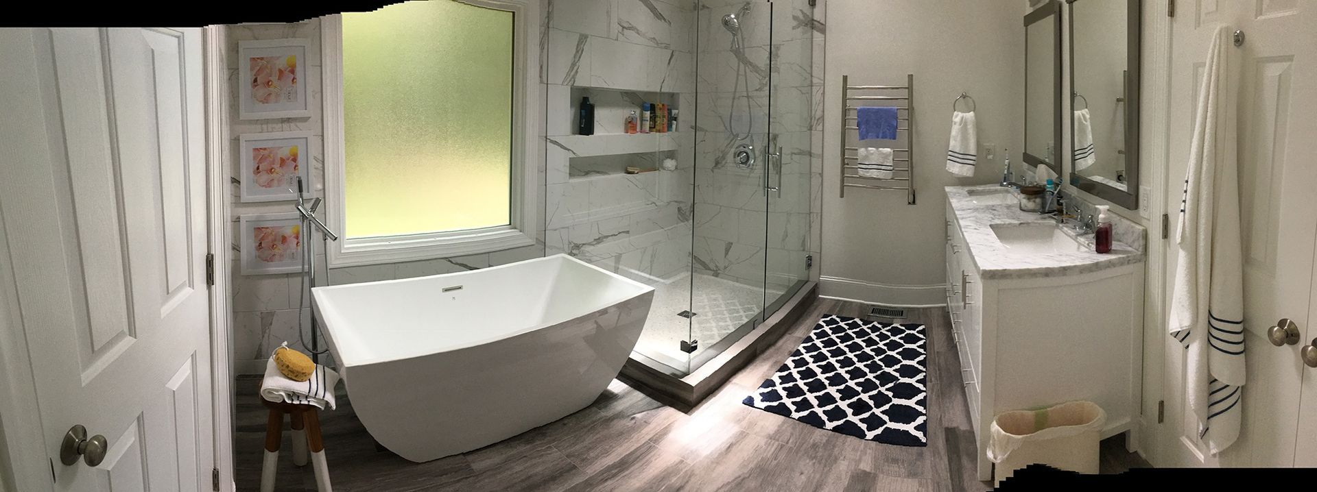 Modern bathroom with a freestanding tub, glass shower, double vanity, and a patterned rug.