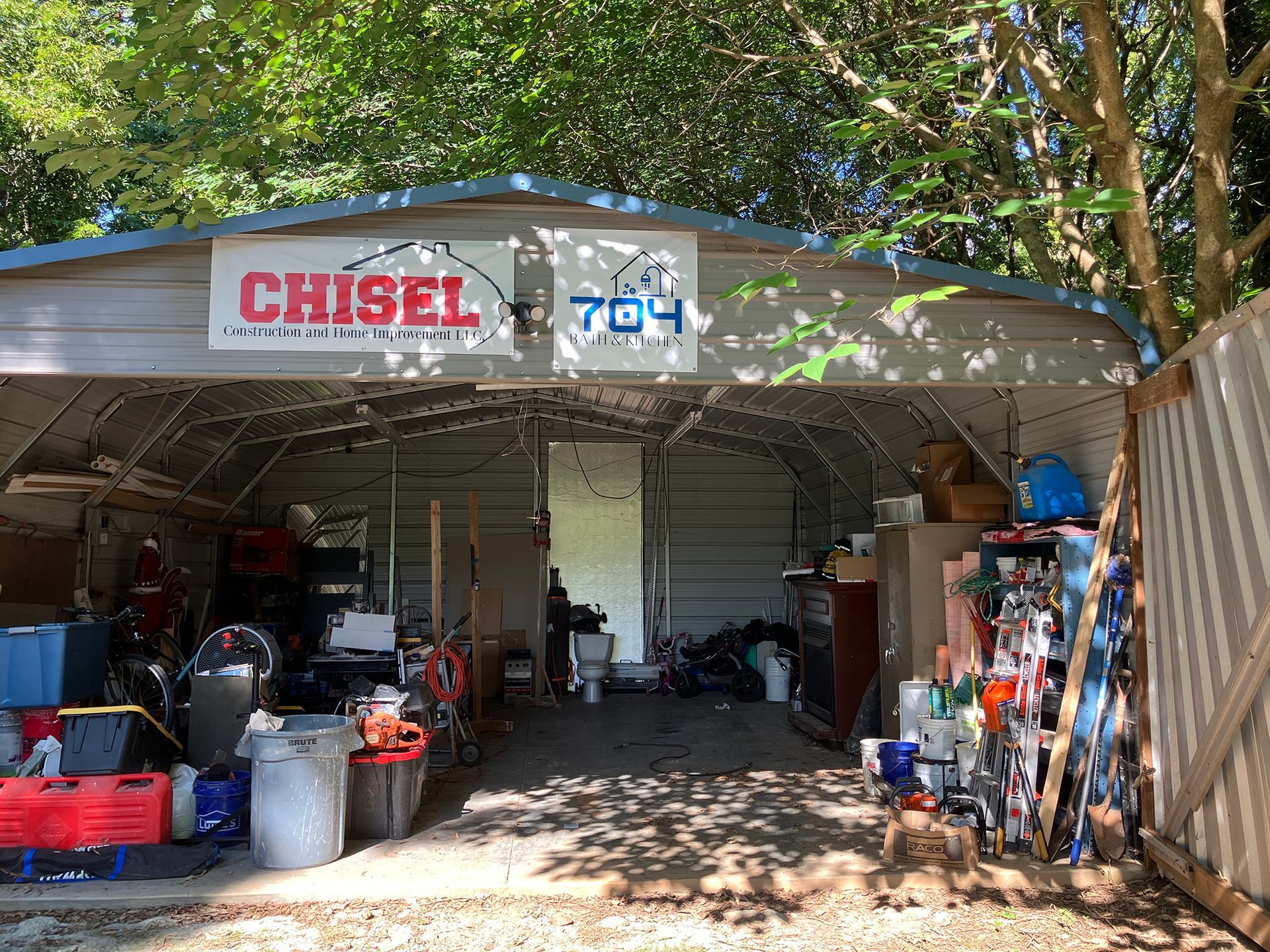 Open-air metal shed filled with items.  Signs read 