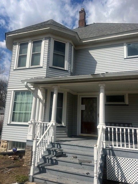 A large white house with a porch and stairs
