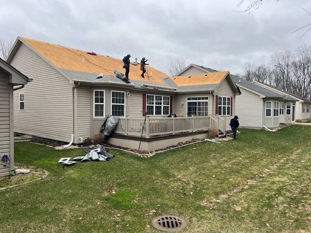 A group of people are working on the roof of a house.