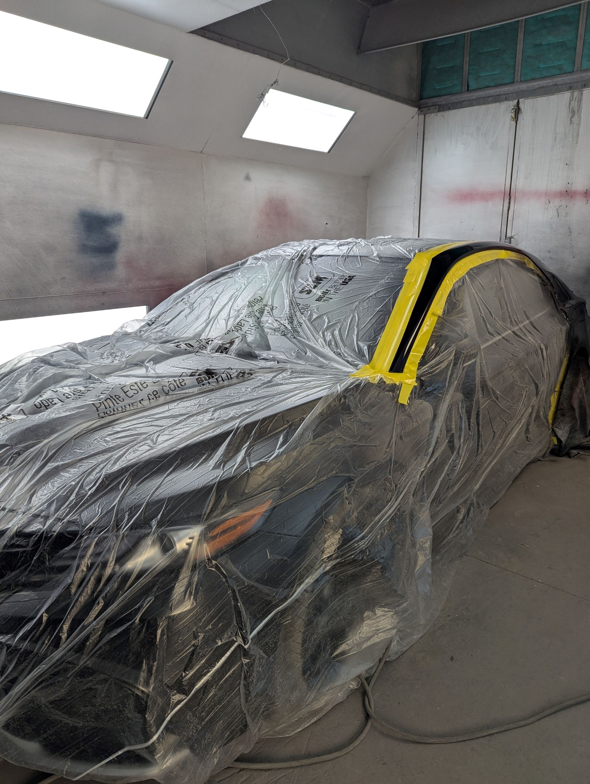 A man is standing in a garage holding a spray gun