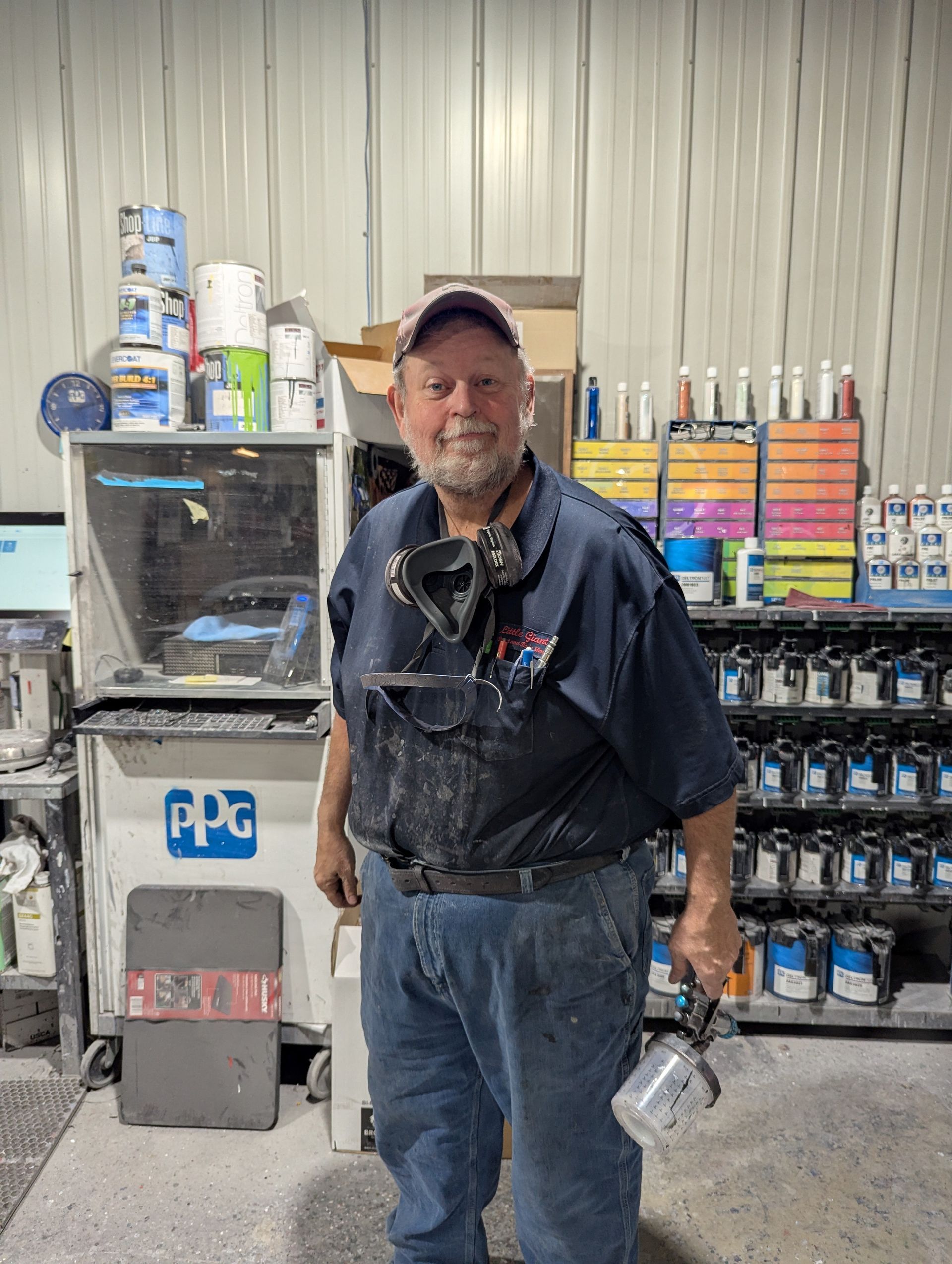 A man is standing in a garage holding a spray gun