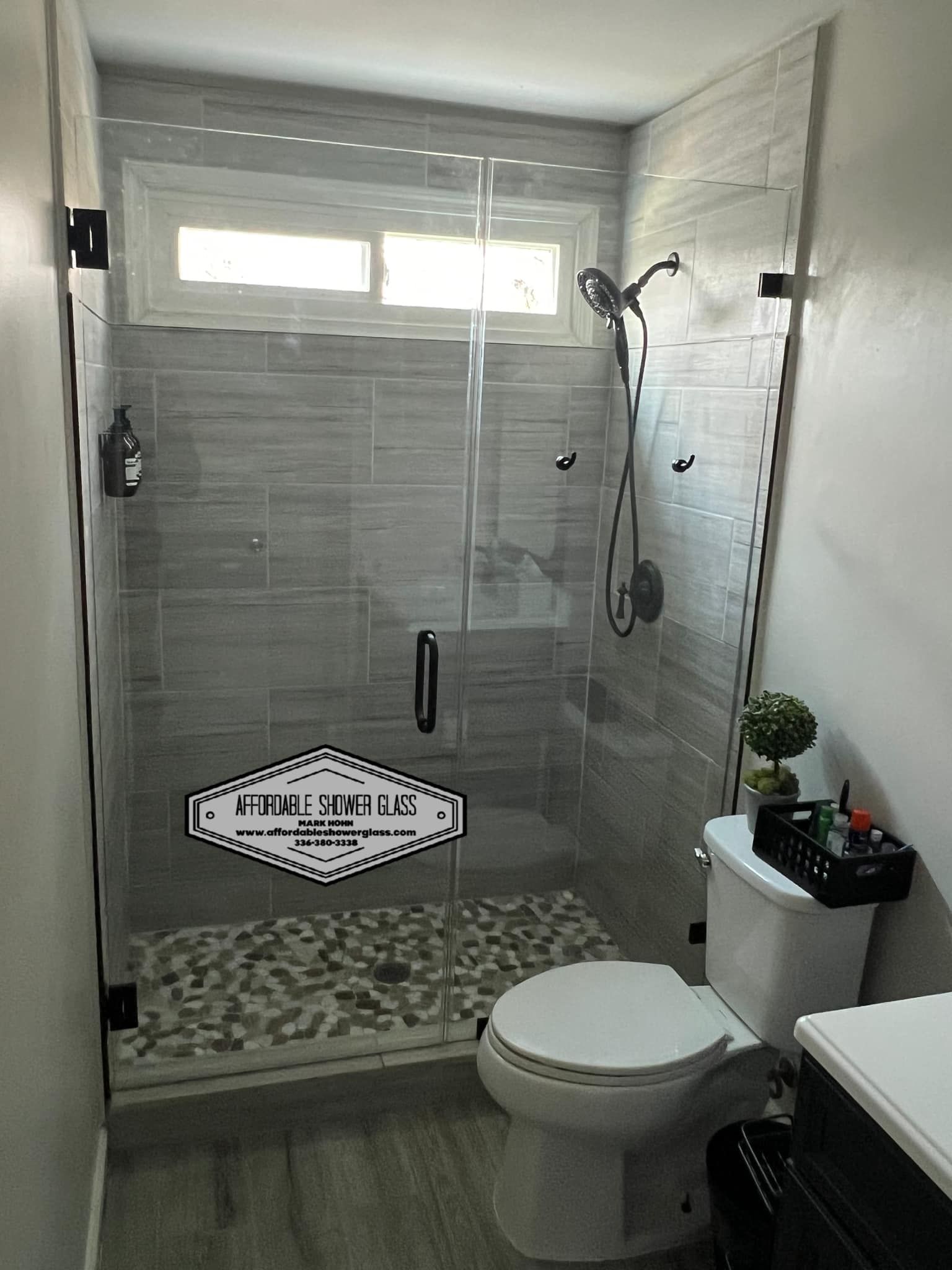 A bathroom with a toilet, shower, and window.