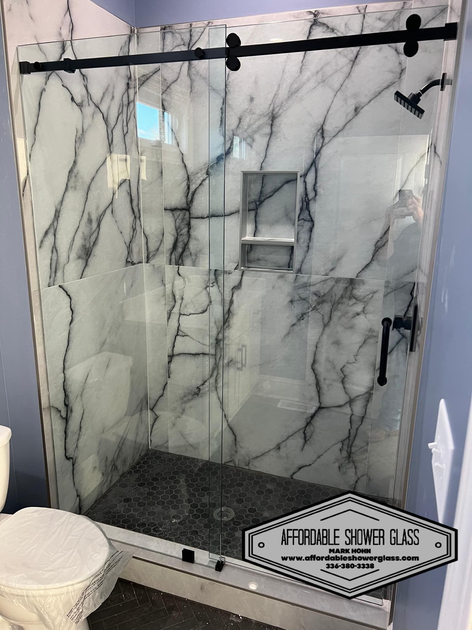 A bathroom with a marble shower and a toilet.