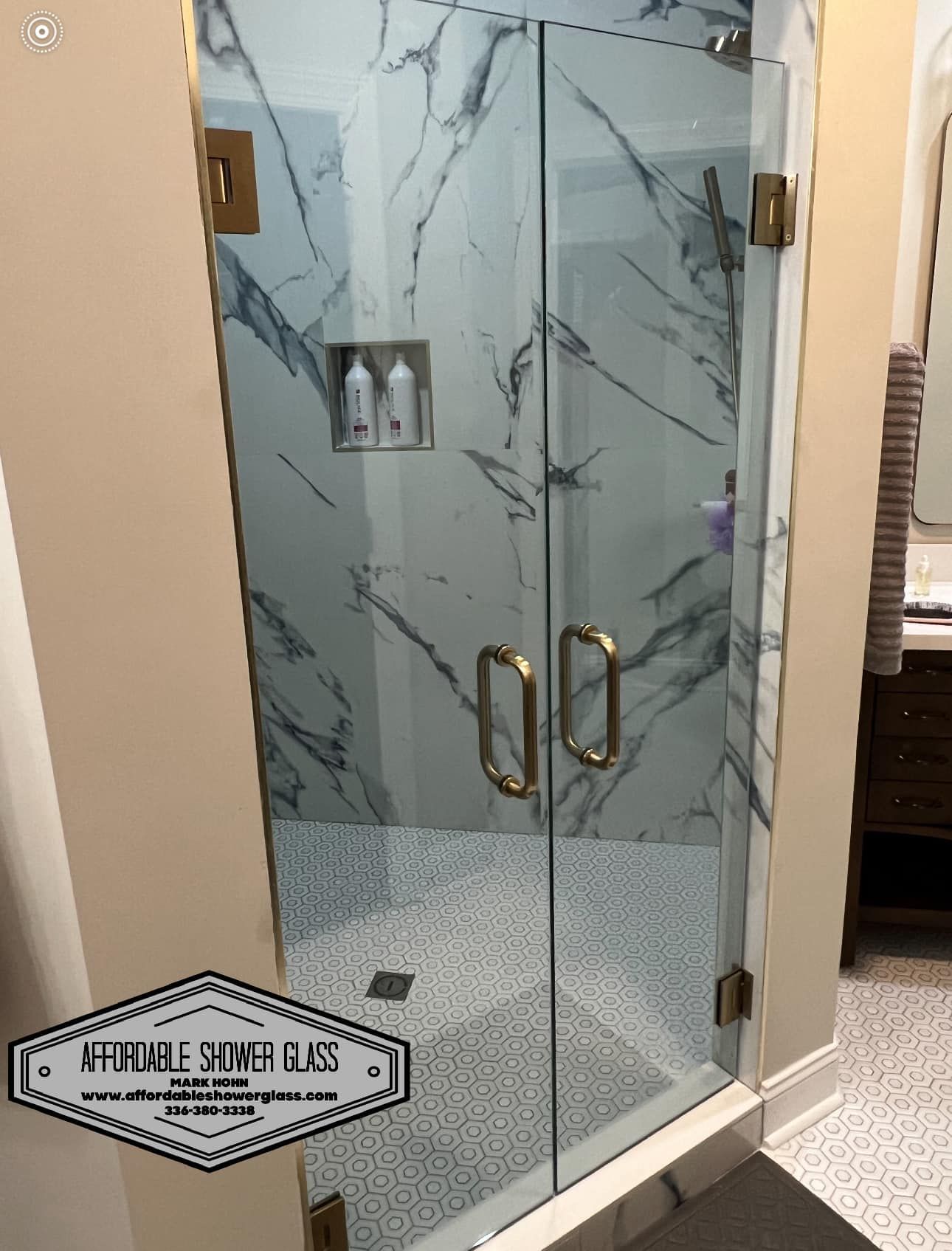 A bathroom with a glass shower door and a marble wall.