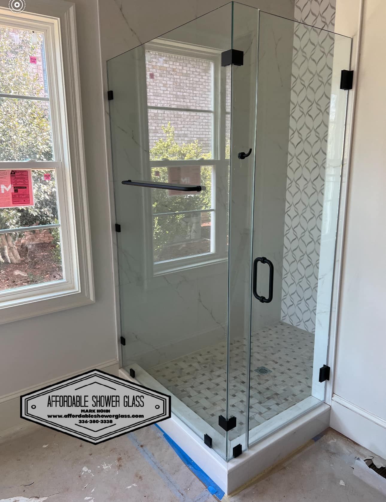 A bathroom with a shower stall and a window.