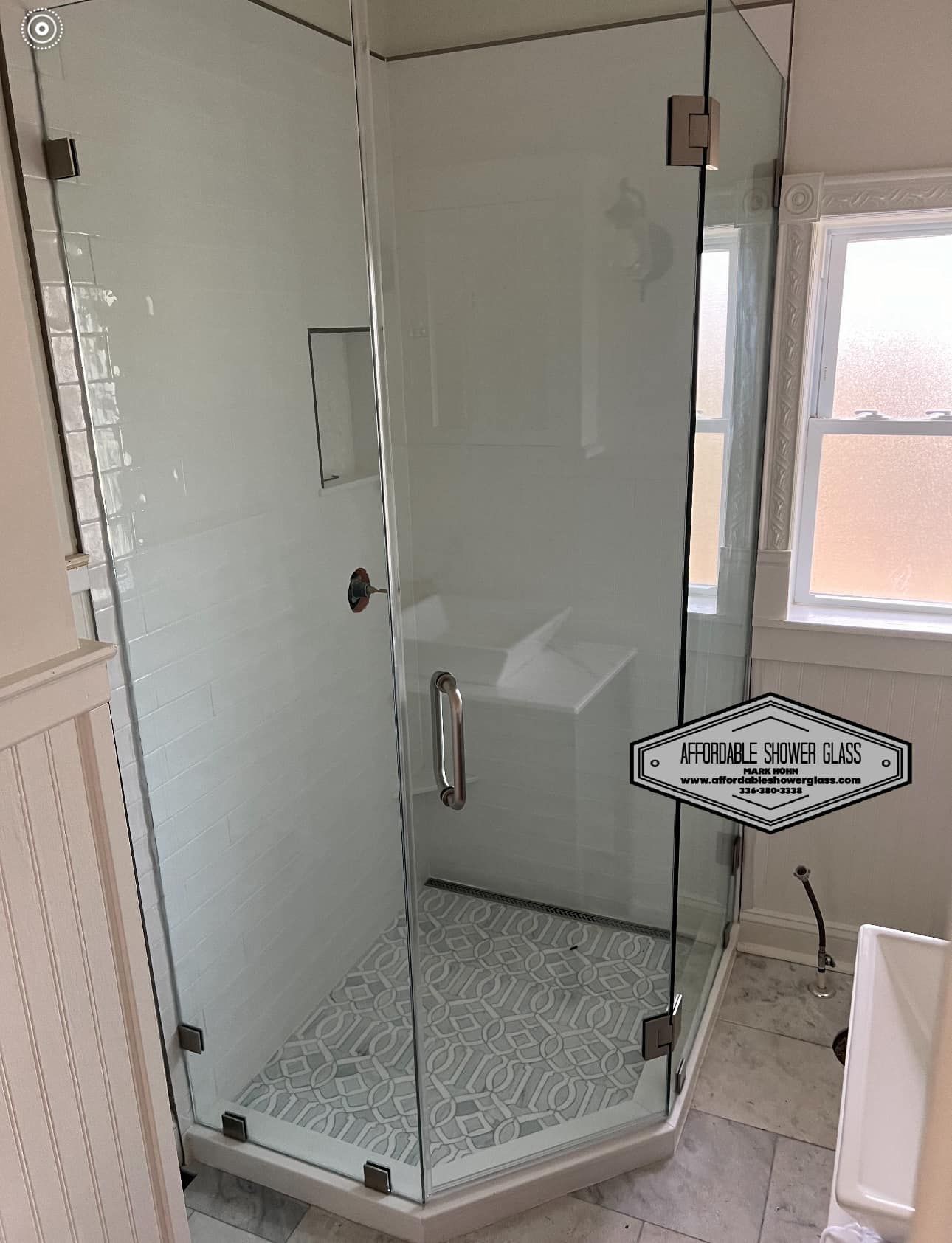 A bathroom with a shower stall and a window.