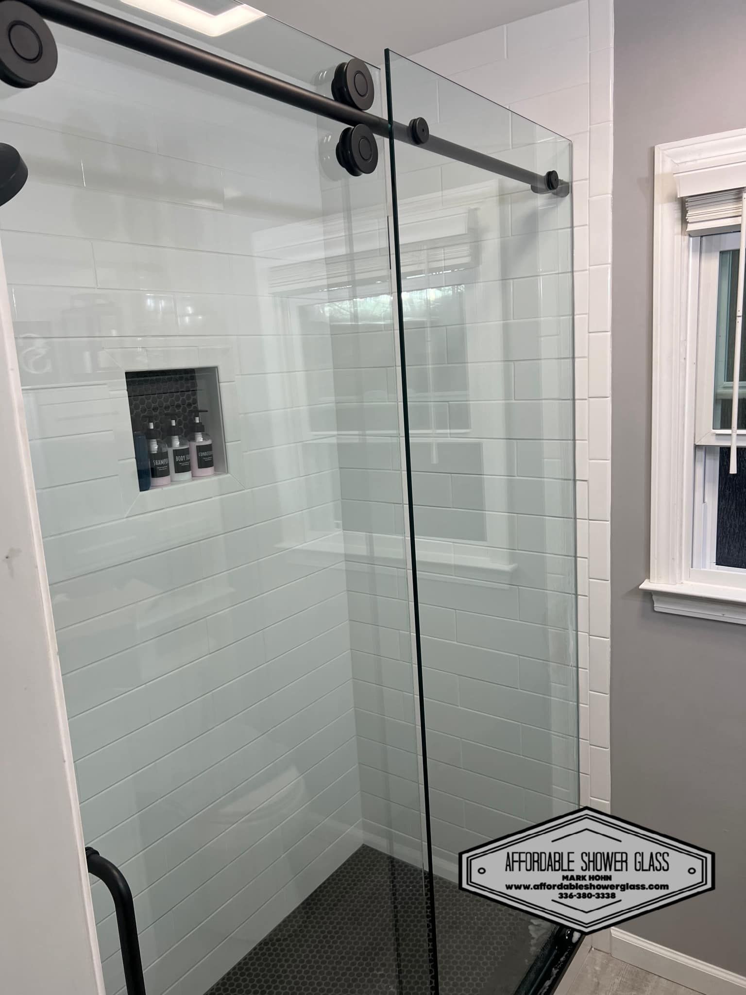 A bathroom with a sliding glass shower door and a window.