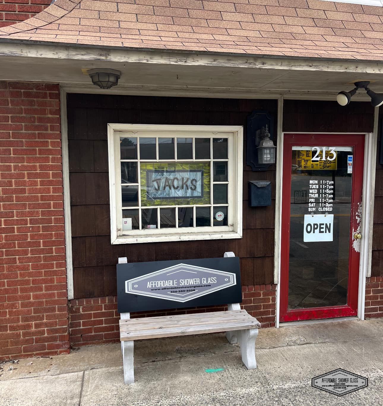 A brick building with a bench in front of it that says jacks