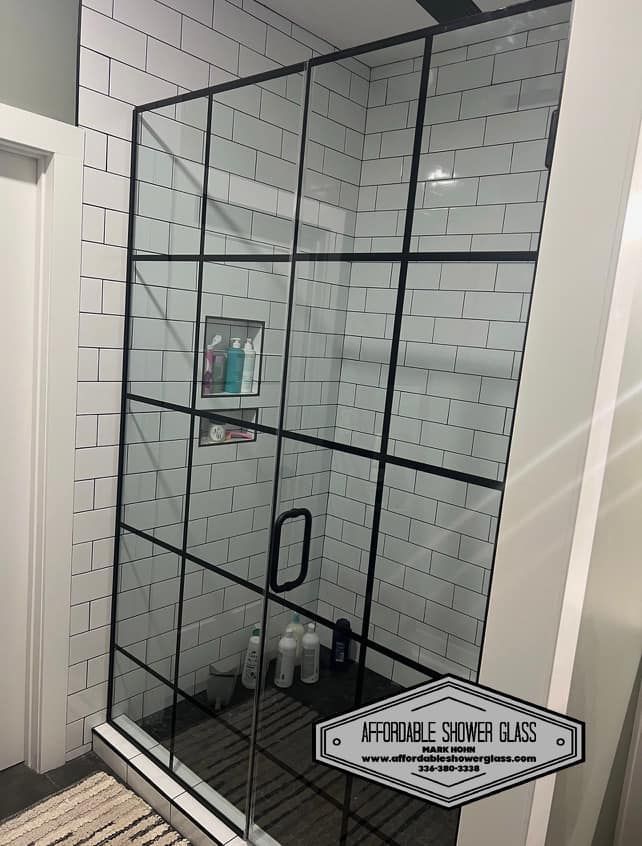 A bathroom with white subway tiles and a black shower door.