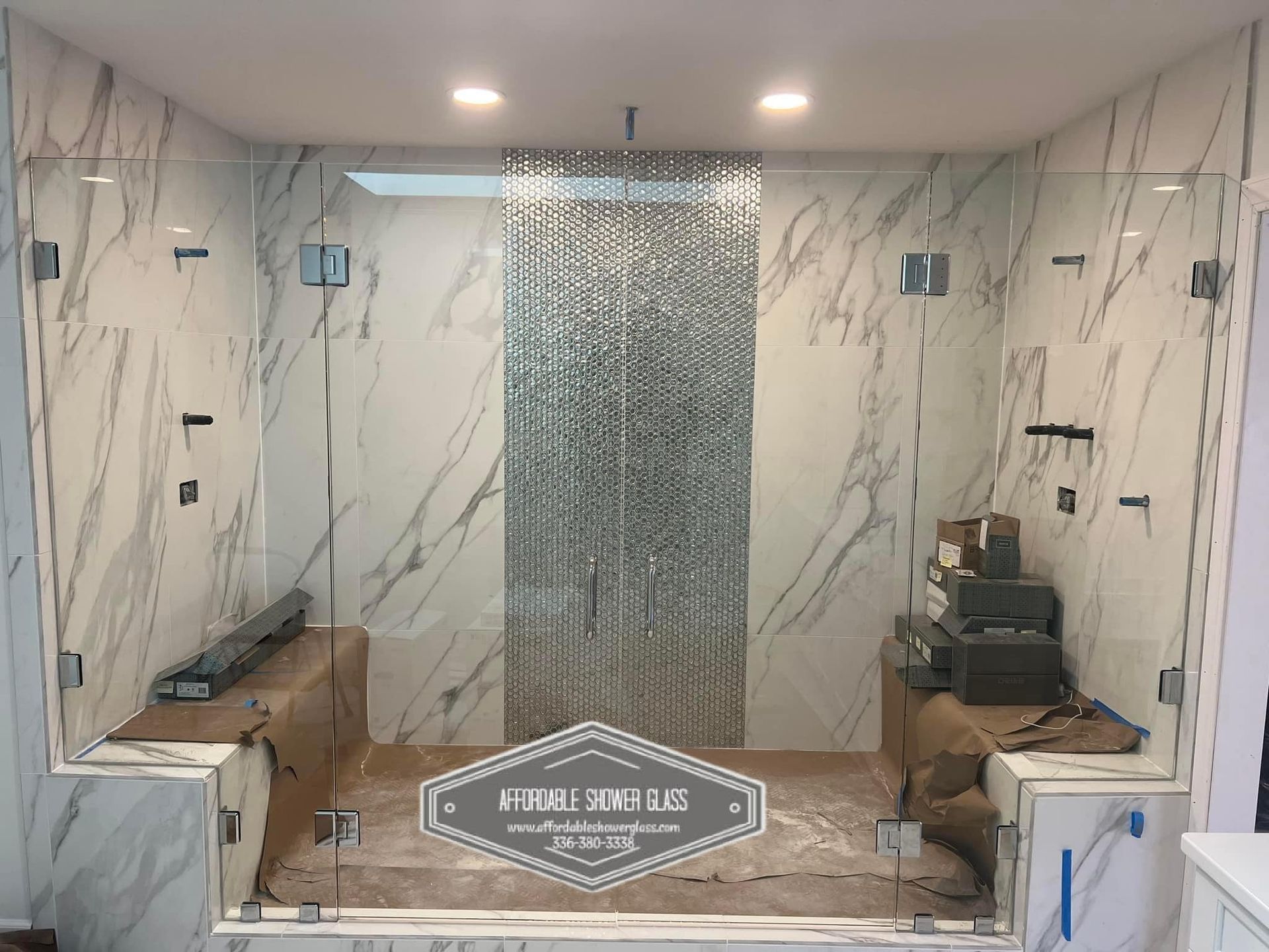 A bathroom with marble walls and a walk in shower with a glass door.