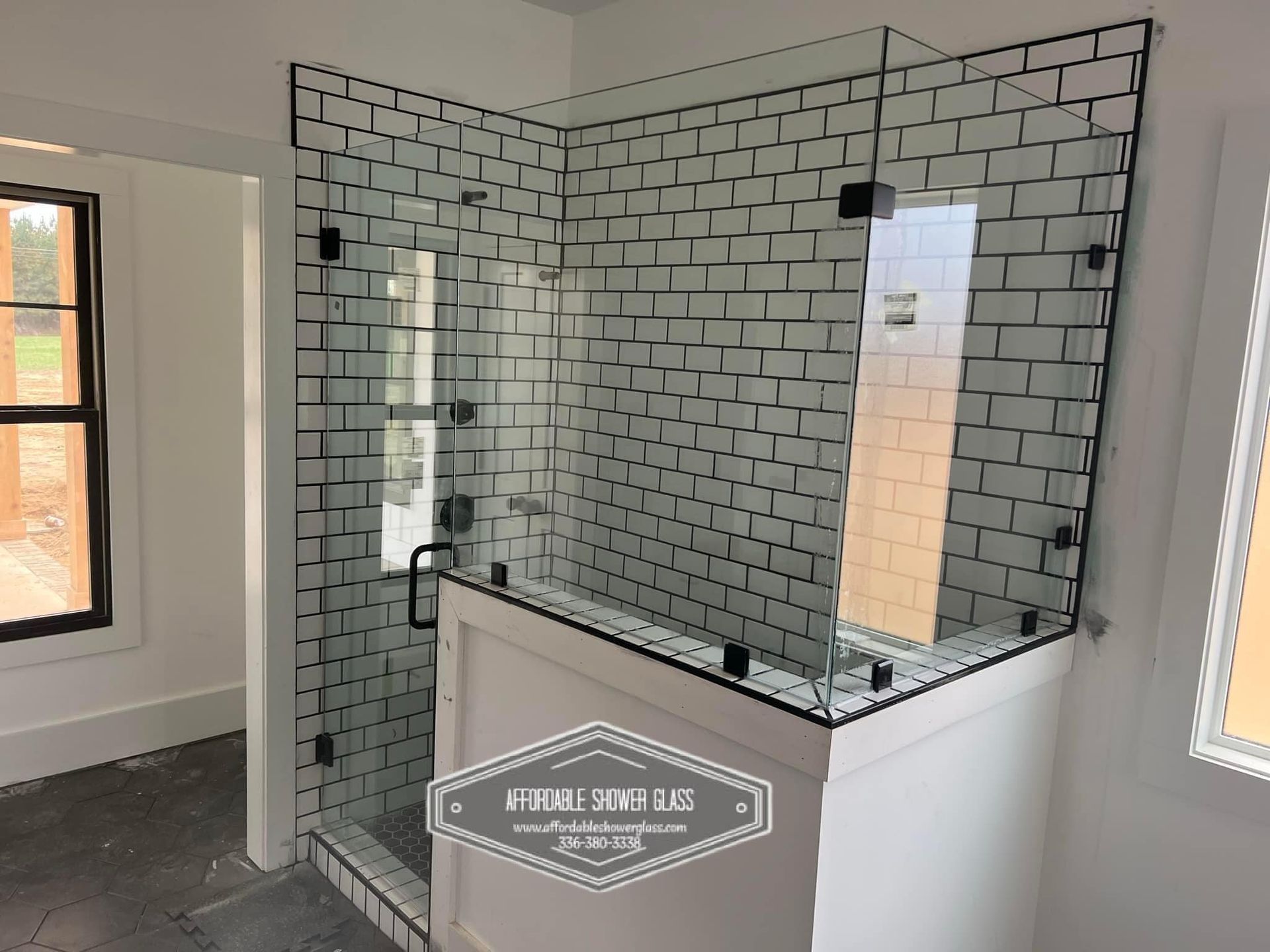 A bathroom with white tiles and a glass shower door