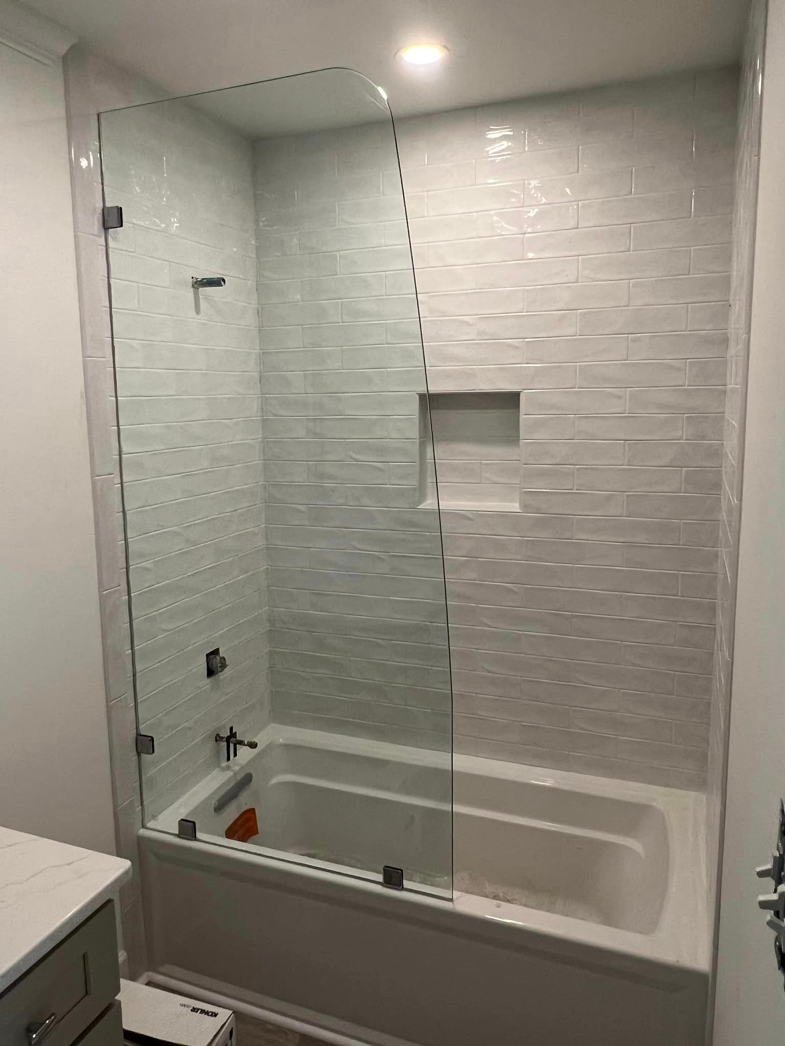A bathroom with a bathtub and a glass shower door.