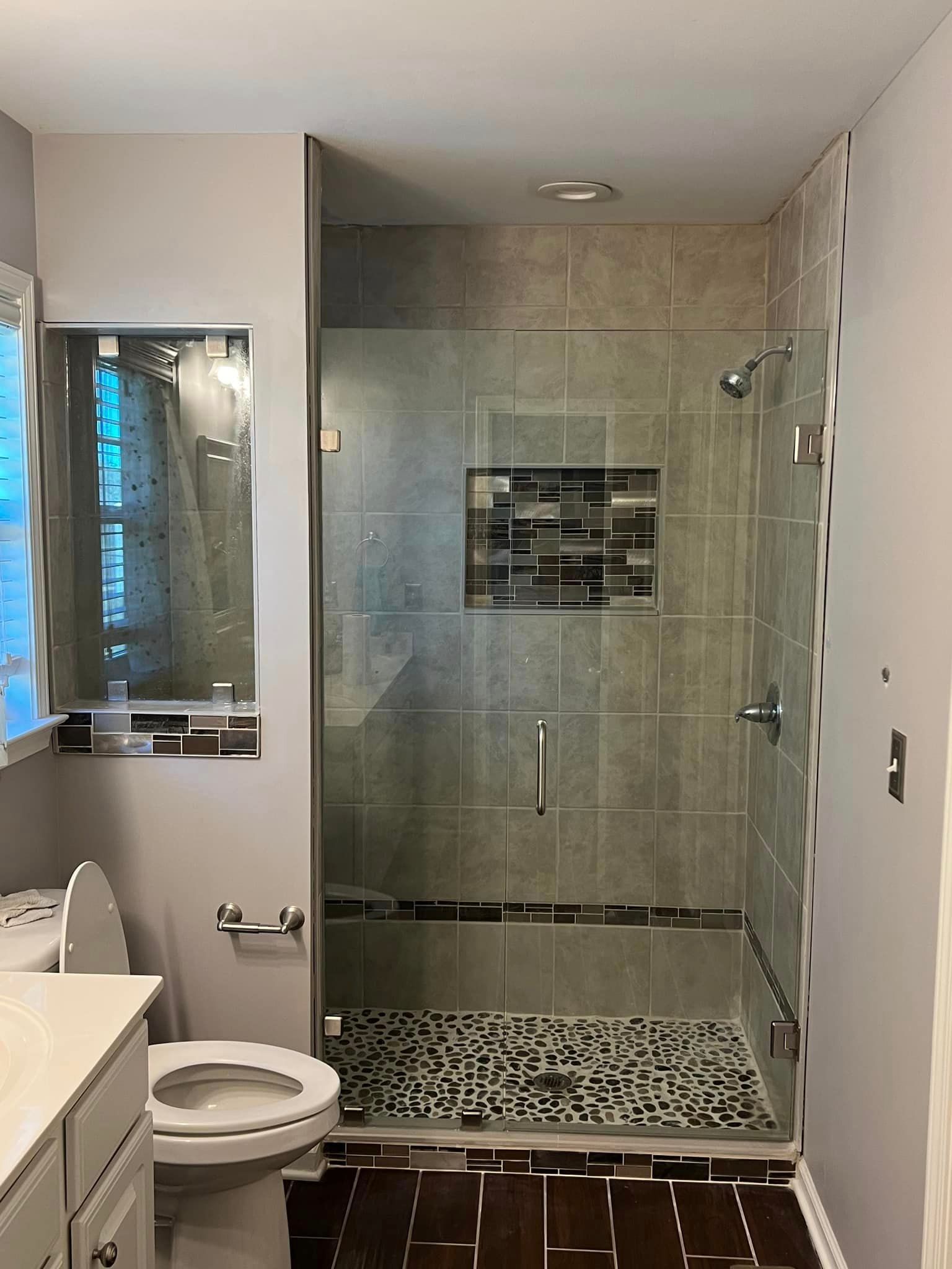 A bathroom with a toilet, sink, and walk in shower.