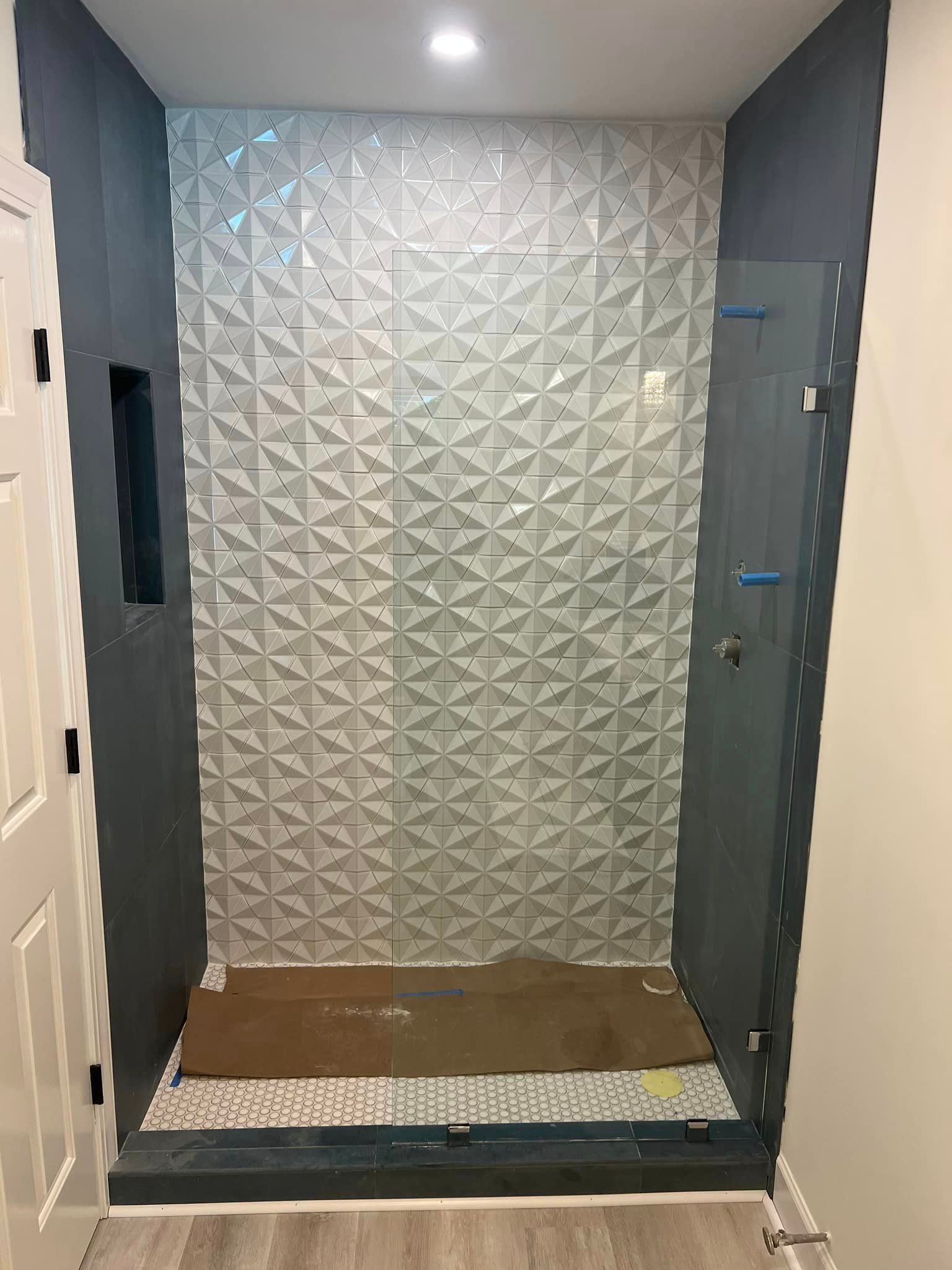 A bathroom with a walk in shower and a tiled wall.