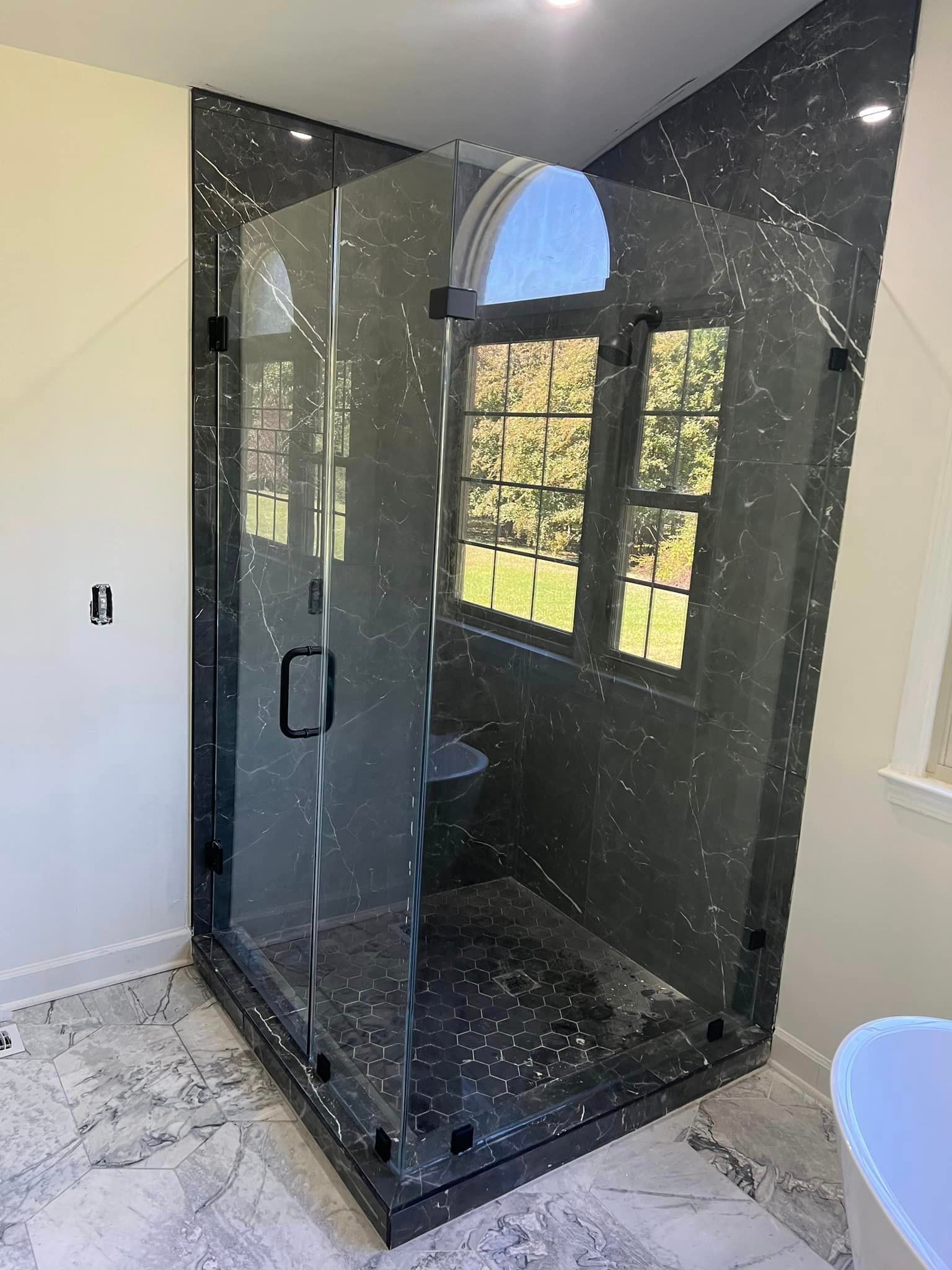 A bathroom with a walk in shower and a tub.