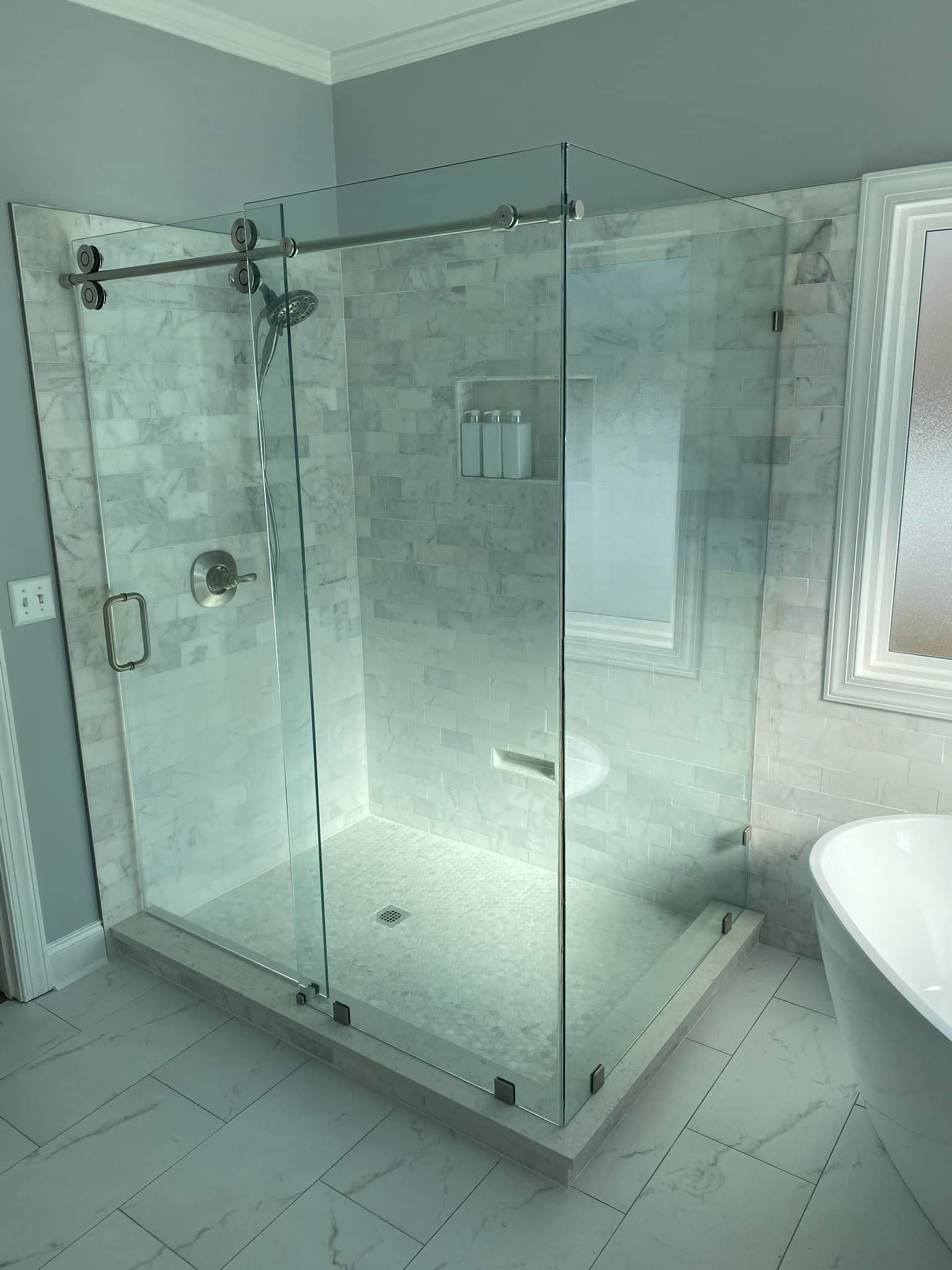 A bathroom with a walk in shower and a tub.