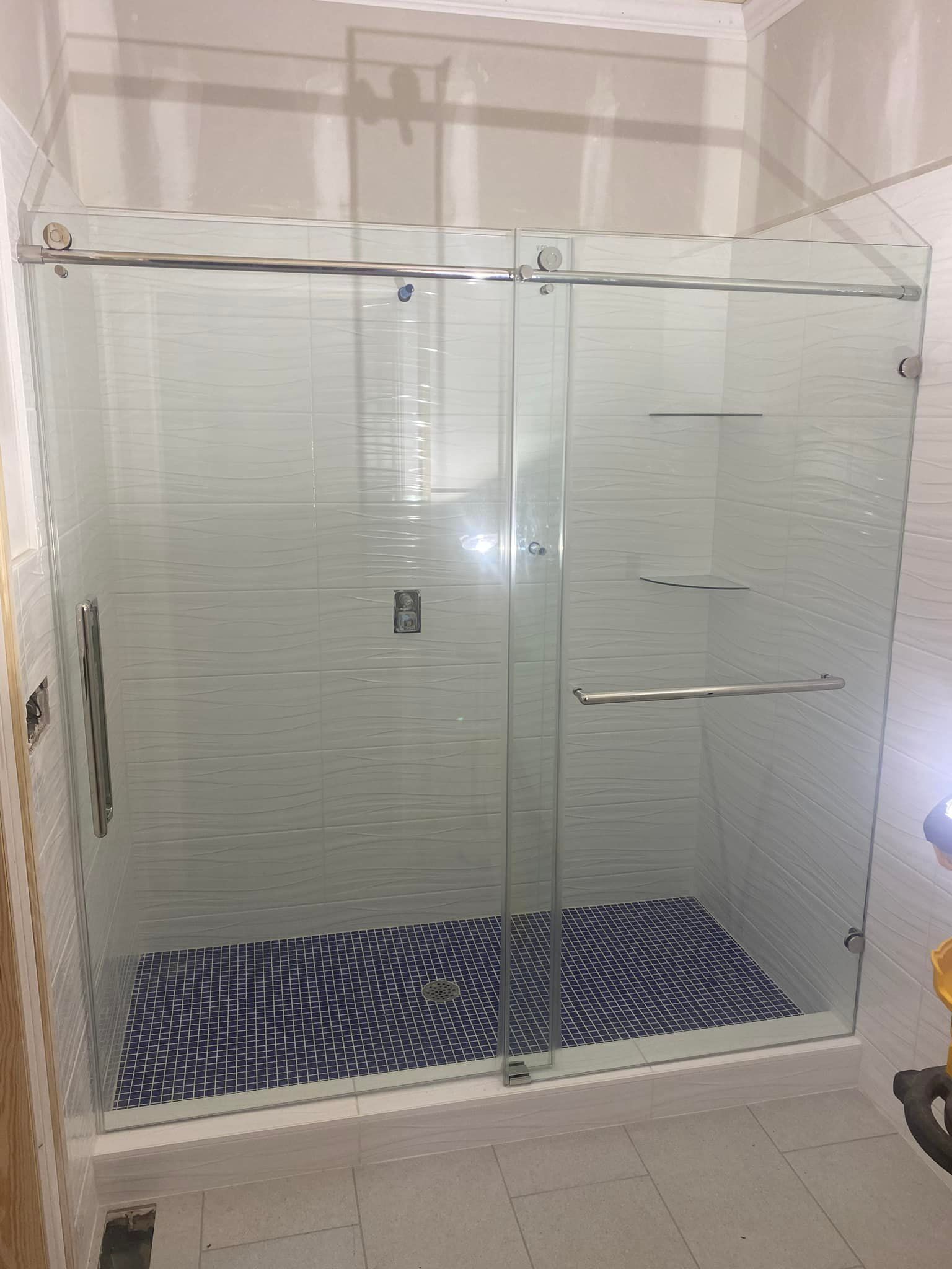 A bathroom with a sliding glass shower door and a mosaic floor.