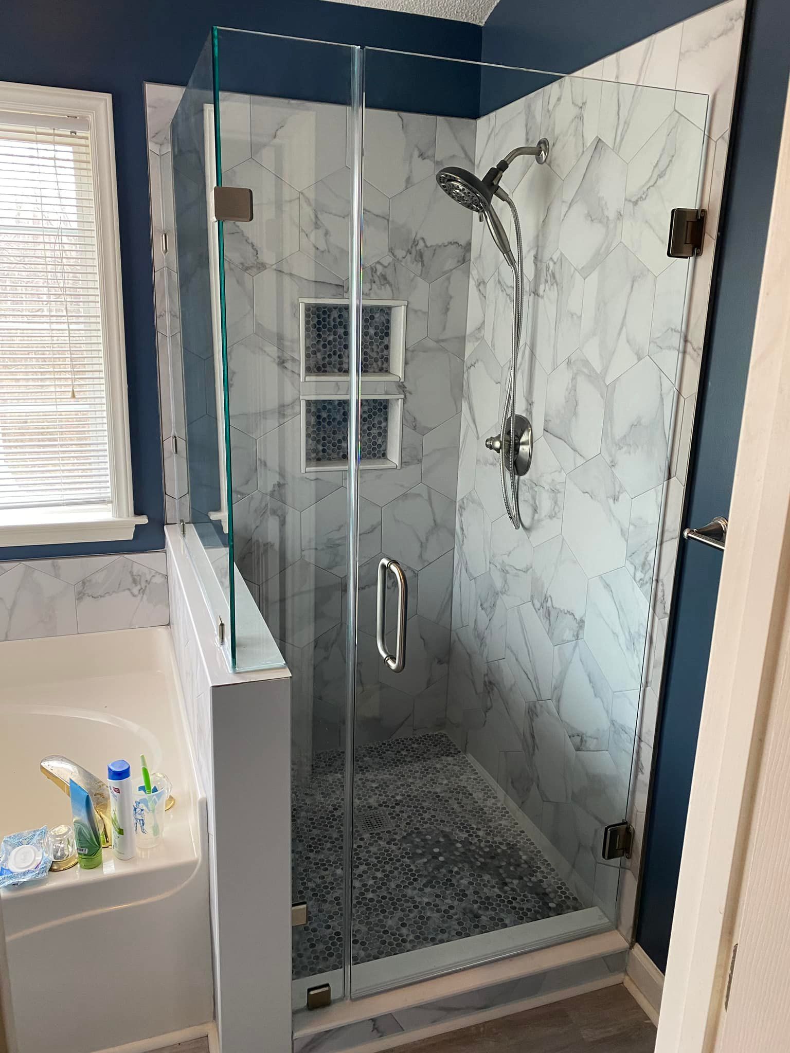 A bathroom with a walk in shower with a glass door.