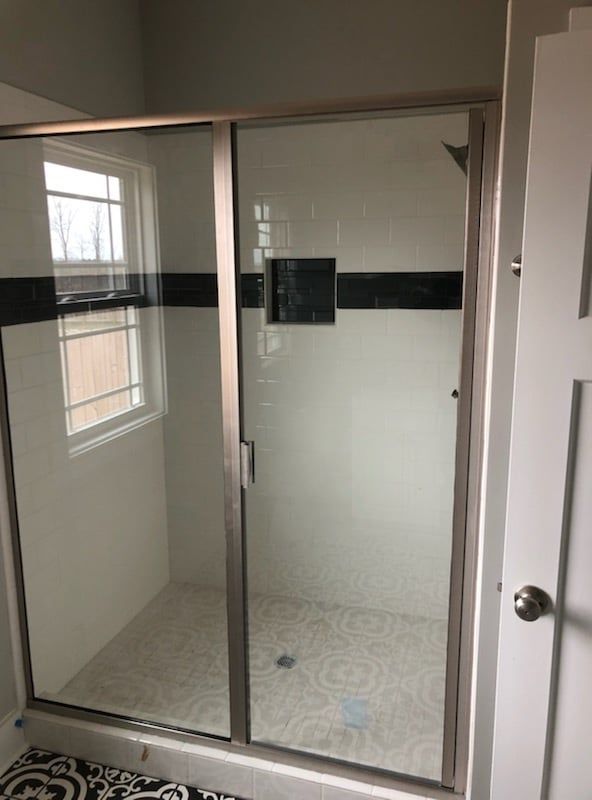 A bathroom with a sliding glass shower door and a window.