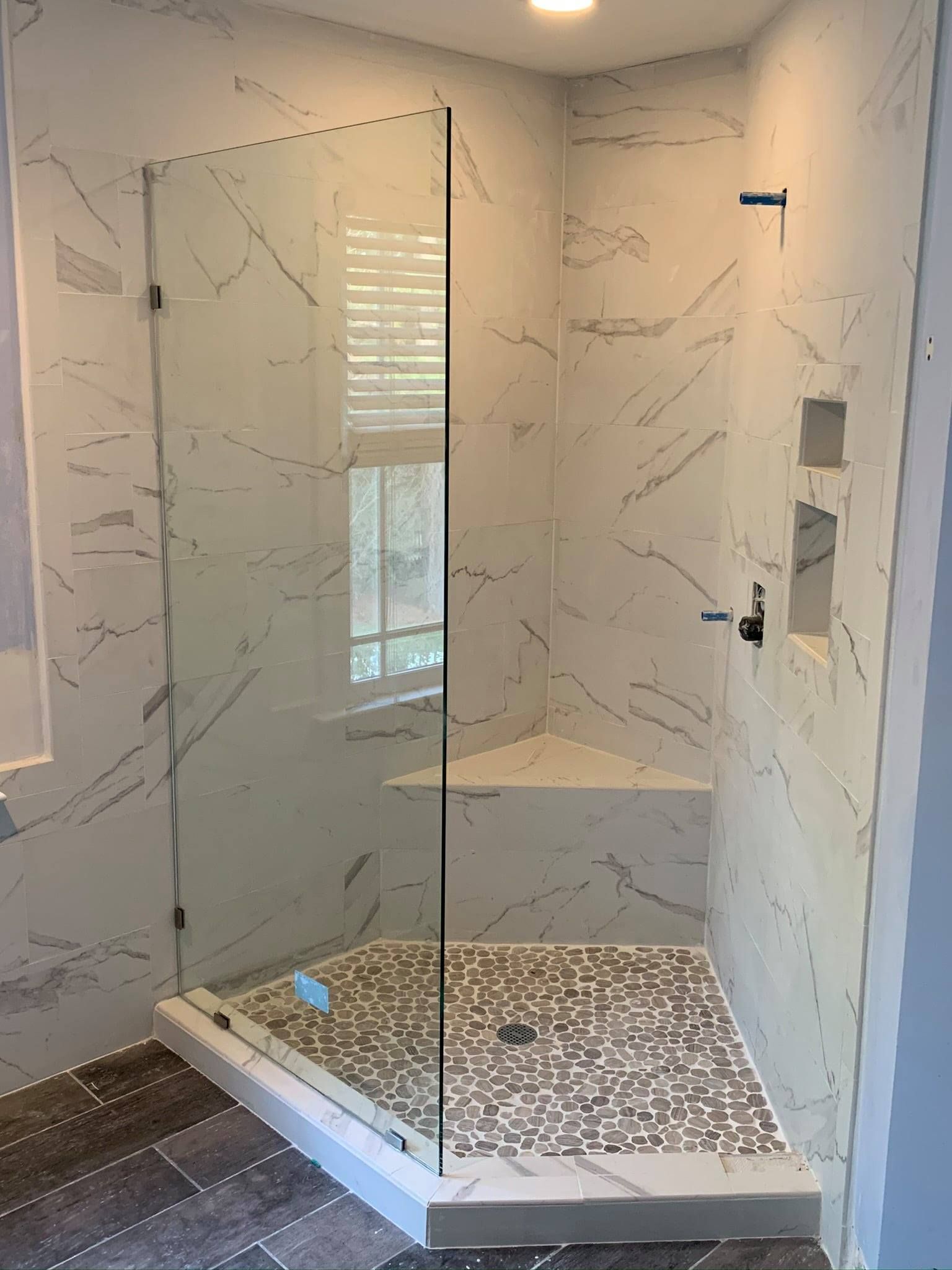 A bathroom with a walk in shower with a glass door.