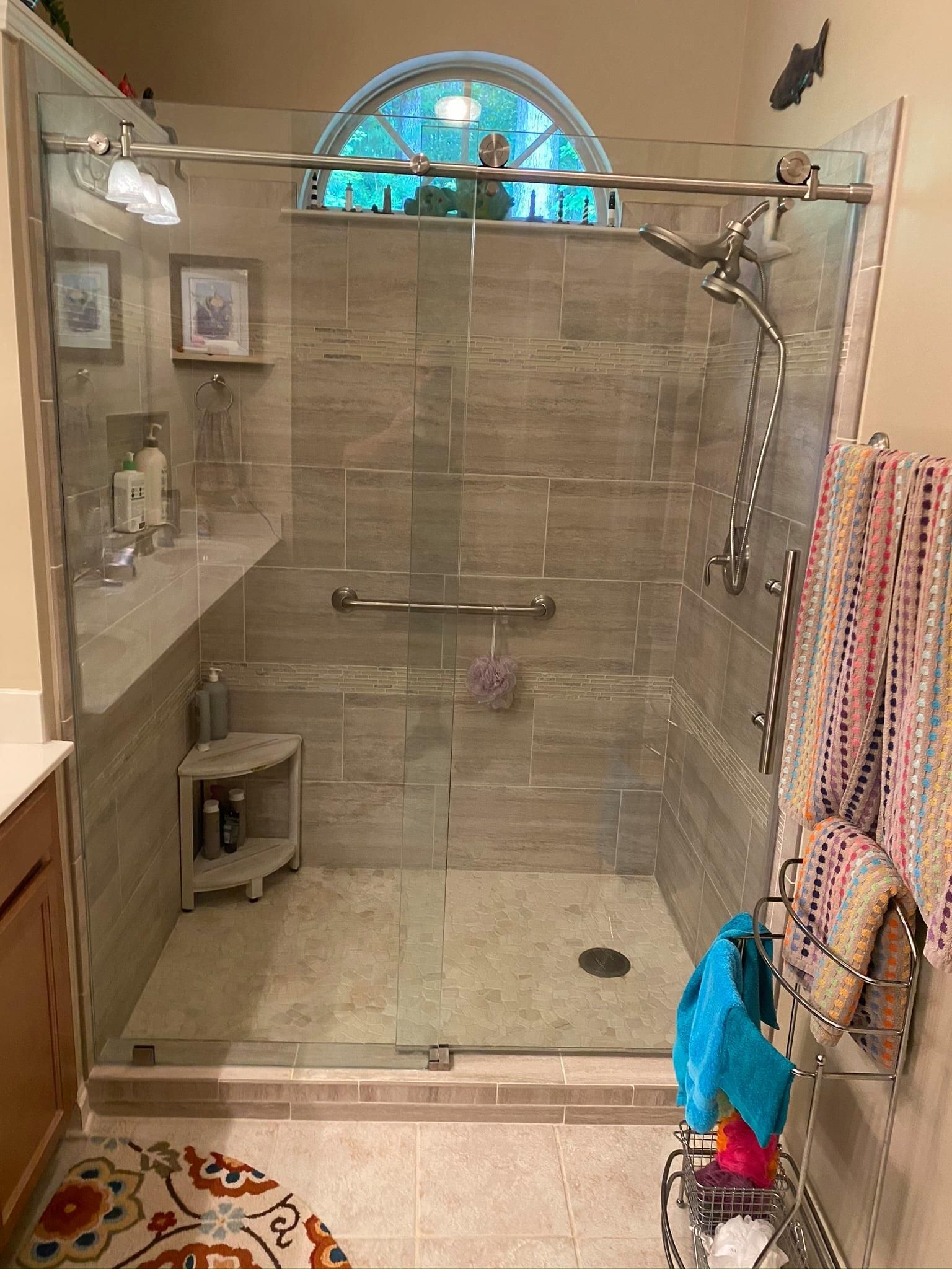 A bathroom with a walk in shower with a sliding glass door.