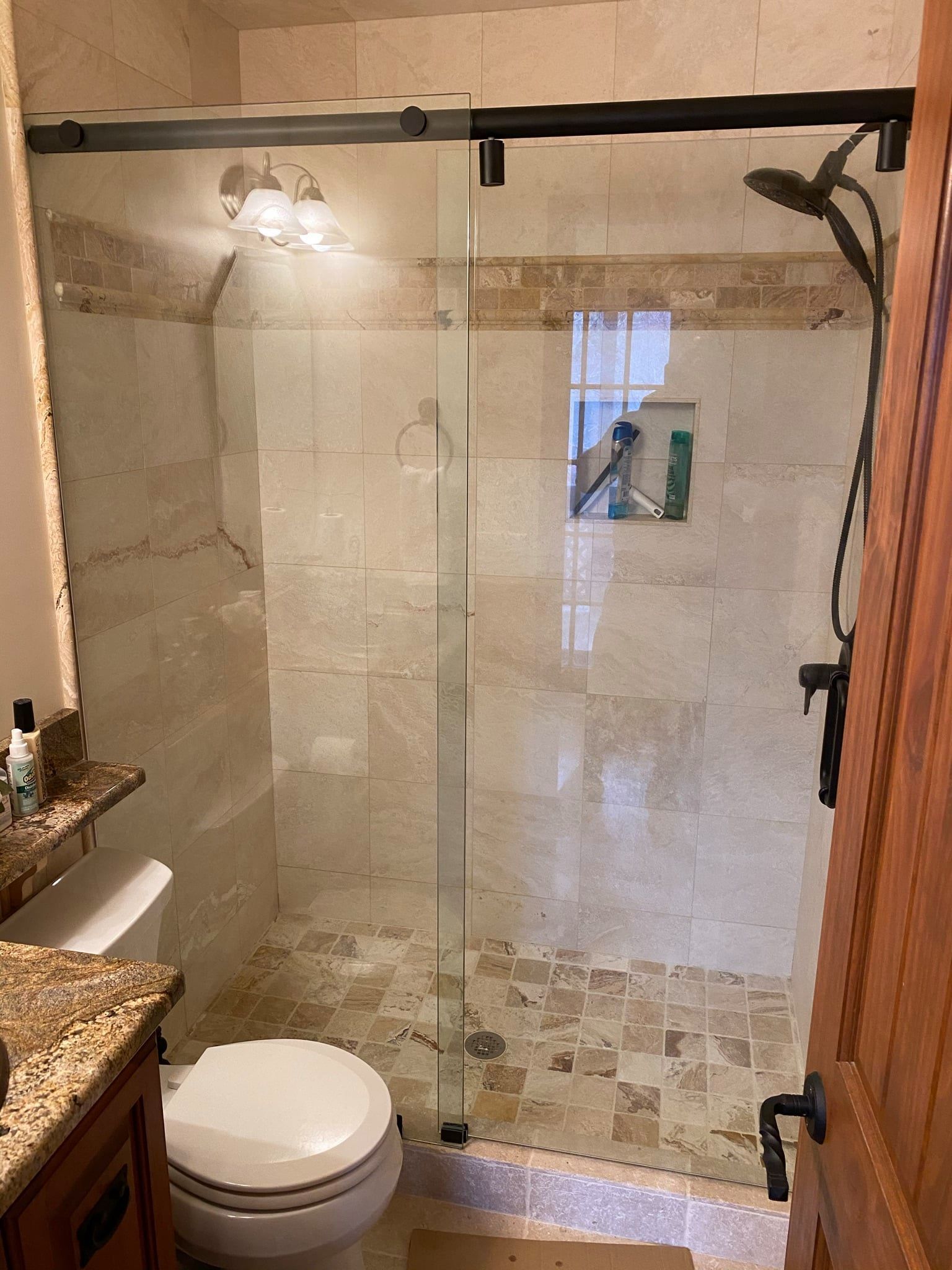 A bathroom with a toilet, sink and shower with a glass door.