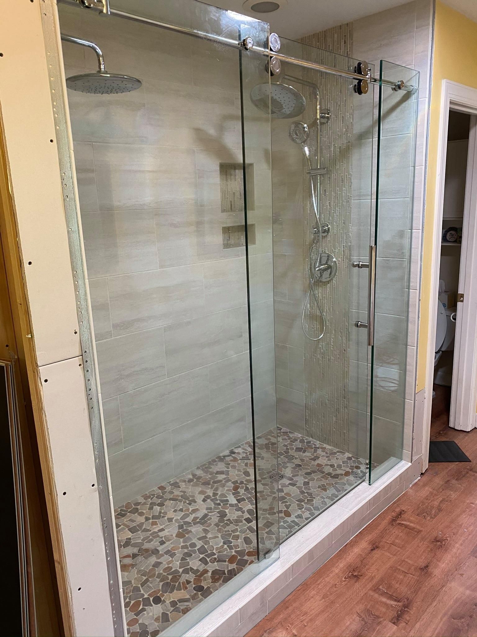 A shower stall with sliding glass doors and a tiled floor in a bathroom.