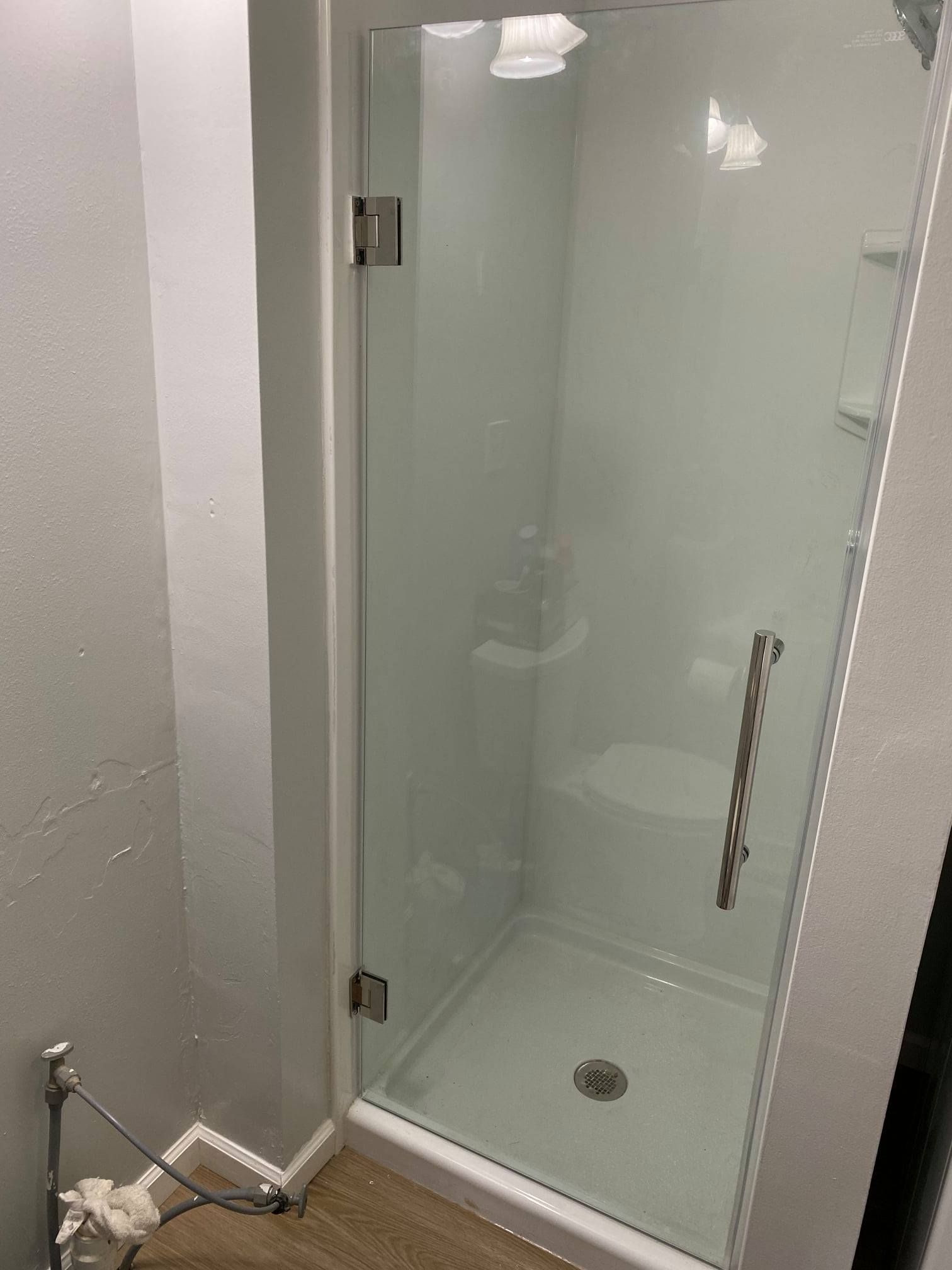A bathroom with a glass shower door and a toilet.