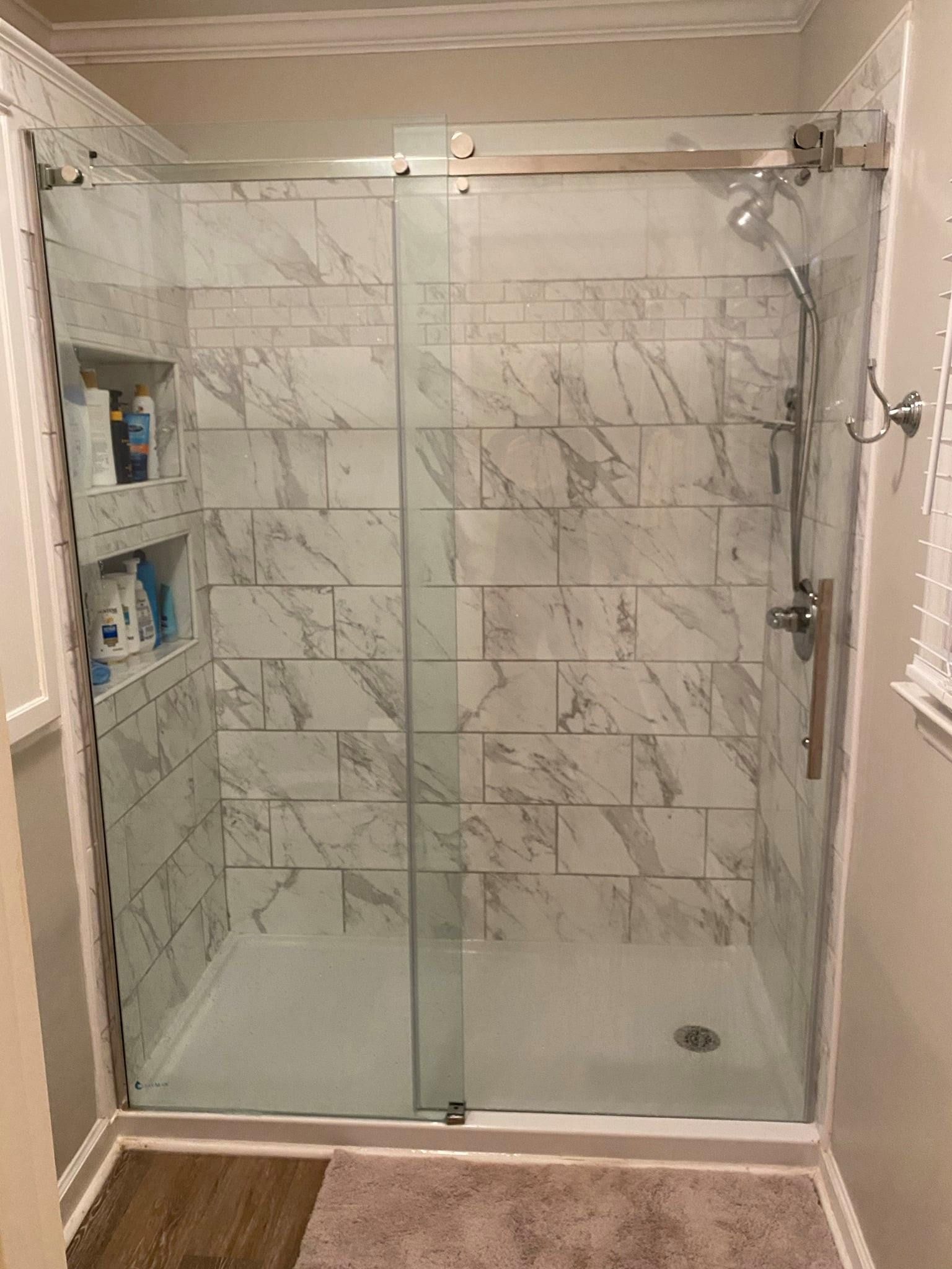 A bathroom with marble tiles and a sliding glass shower door.