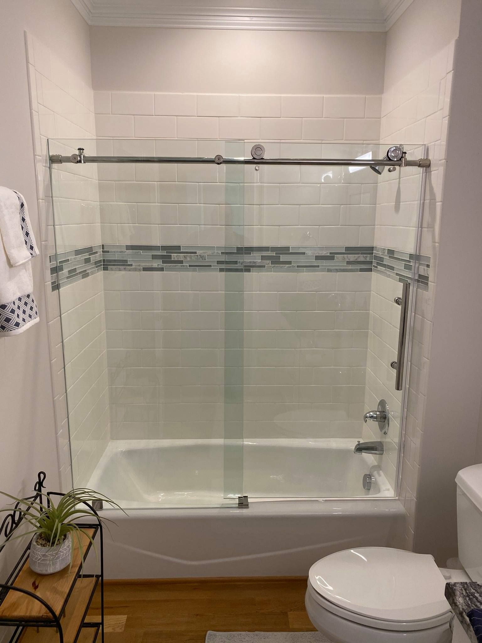A bathroom with a tub, toilet, shower and sliding glass door.