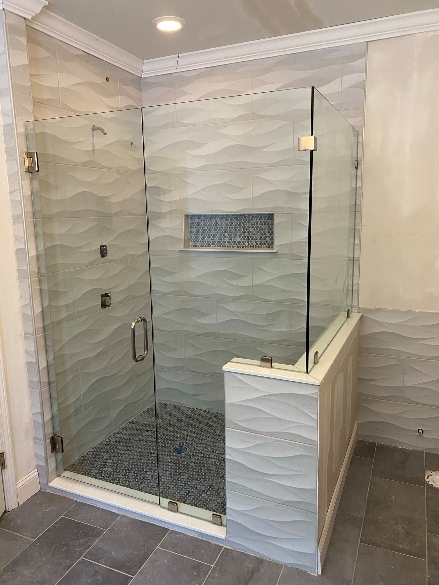 A bathroom with a walk in shower with a glass door.