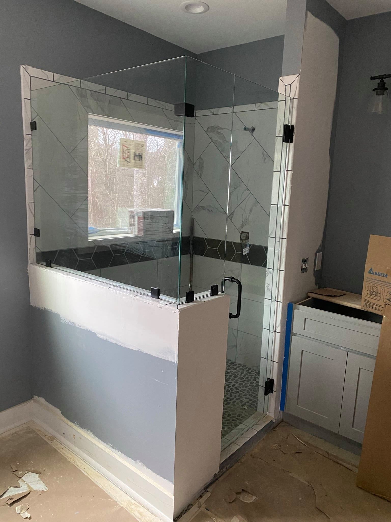 A bathroom with a glass shower door and a window.