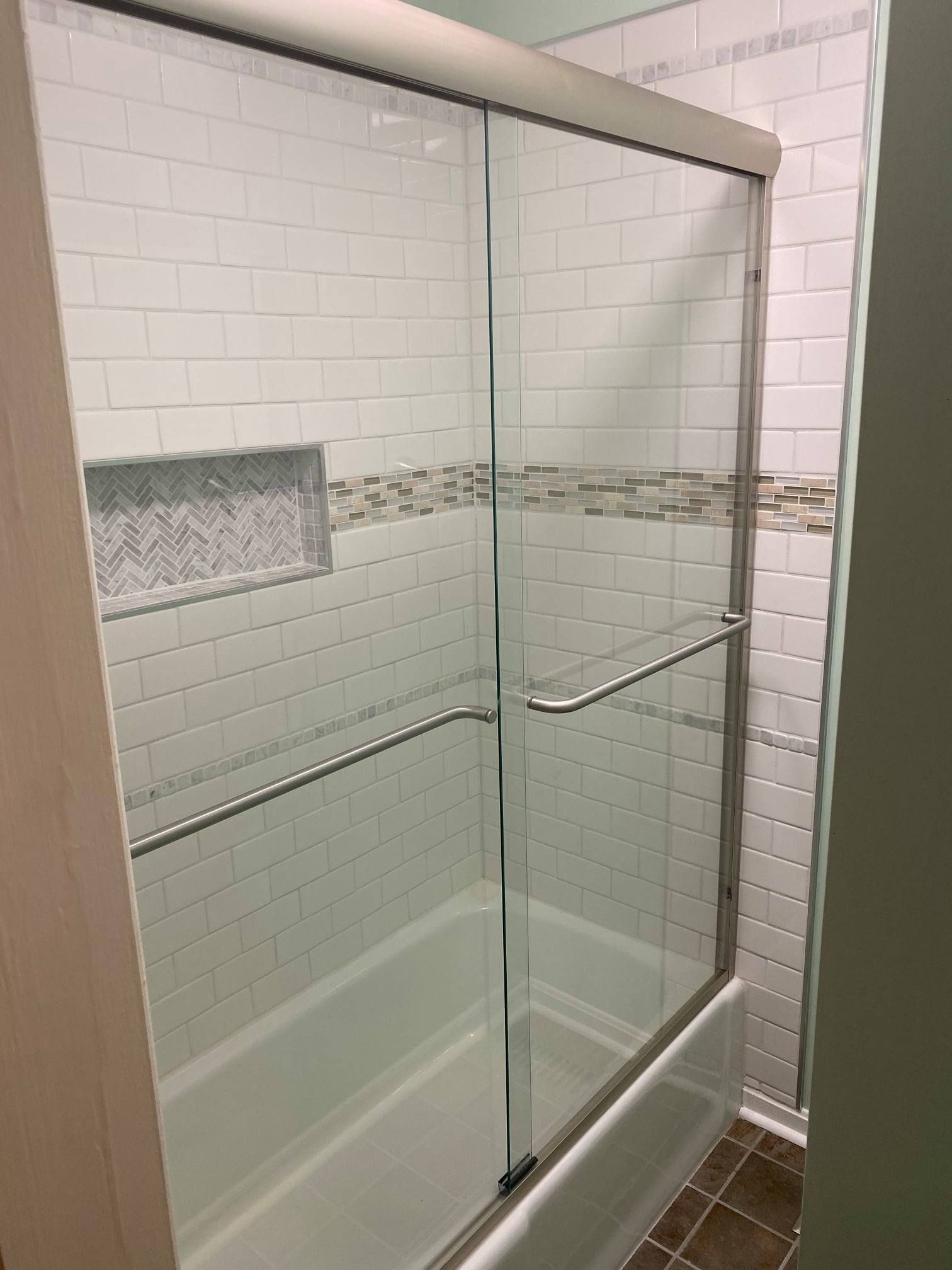 A bathroom with a sliding glass shower door and a bathtub.