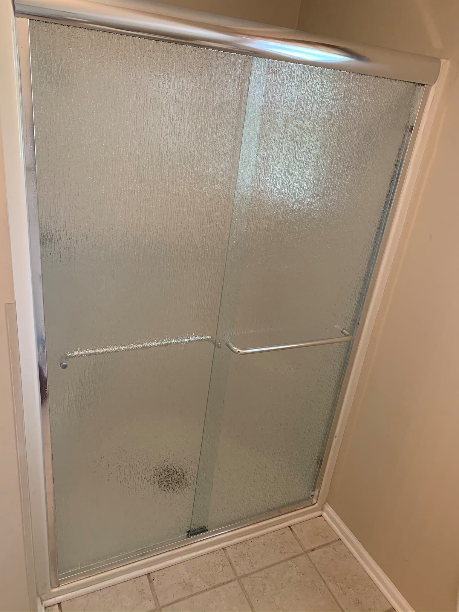A bathroom with a sliding glass shower door and a tiled floor.