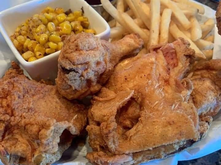 A basket of fried chicken with french fries and corn on the cob.