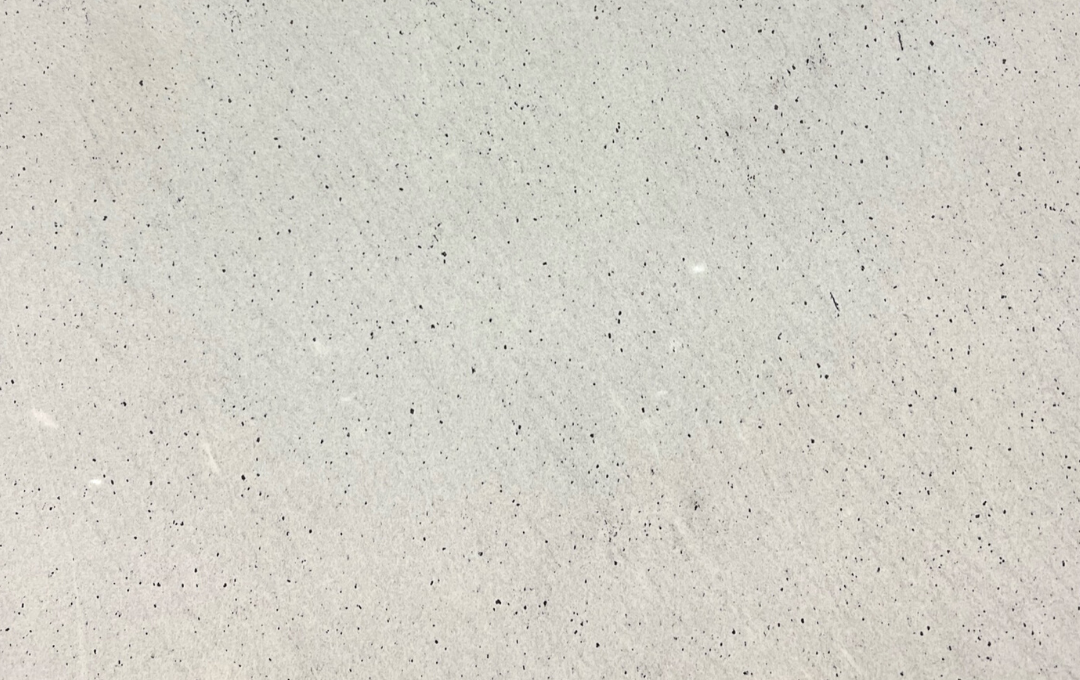 Off-white surface with tiny black flecks, possibly textured or concrete.