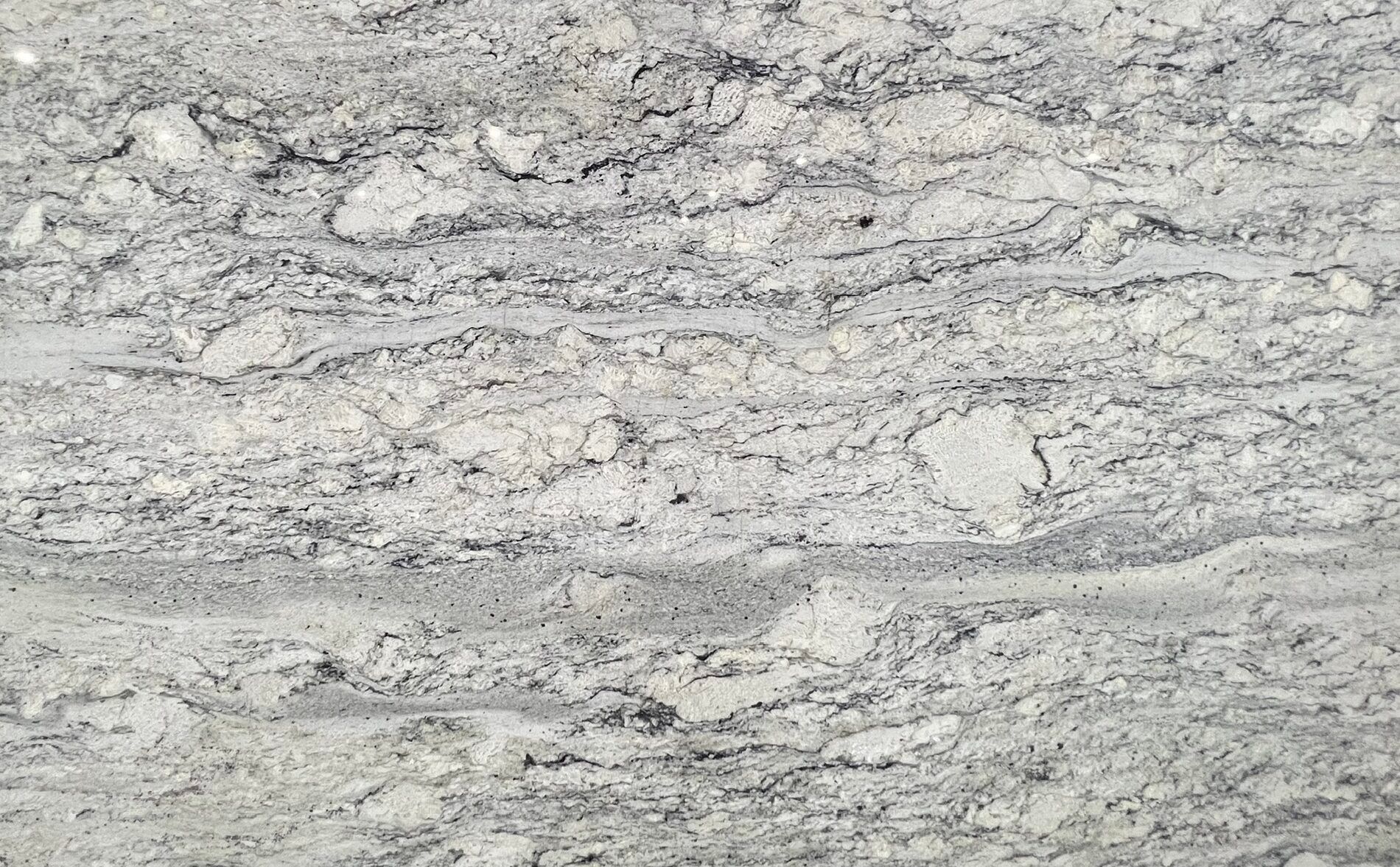 Close-up of white and gray granite with flowing veins and dark speckling.