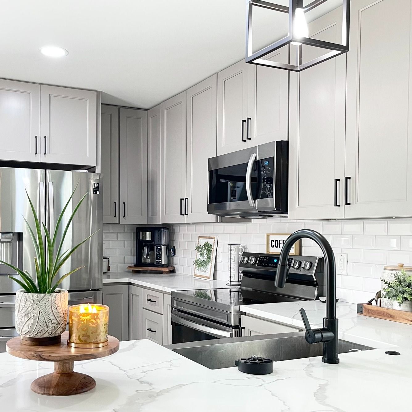 Modern kitchen with gray cabinets, stainless steel appliances, and black faucet.