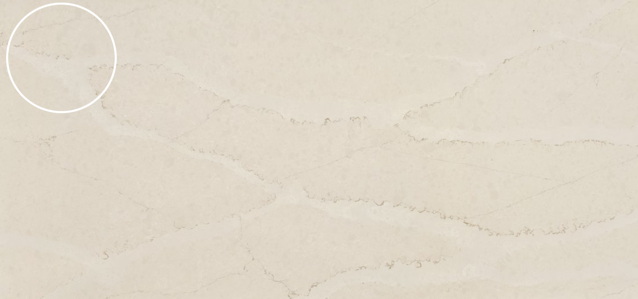Cream-colored surface with subtle light-brown veining, a marble or quartz countertop, with a small section circled.