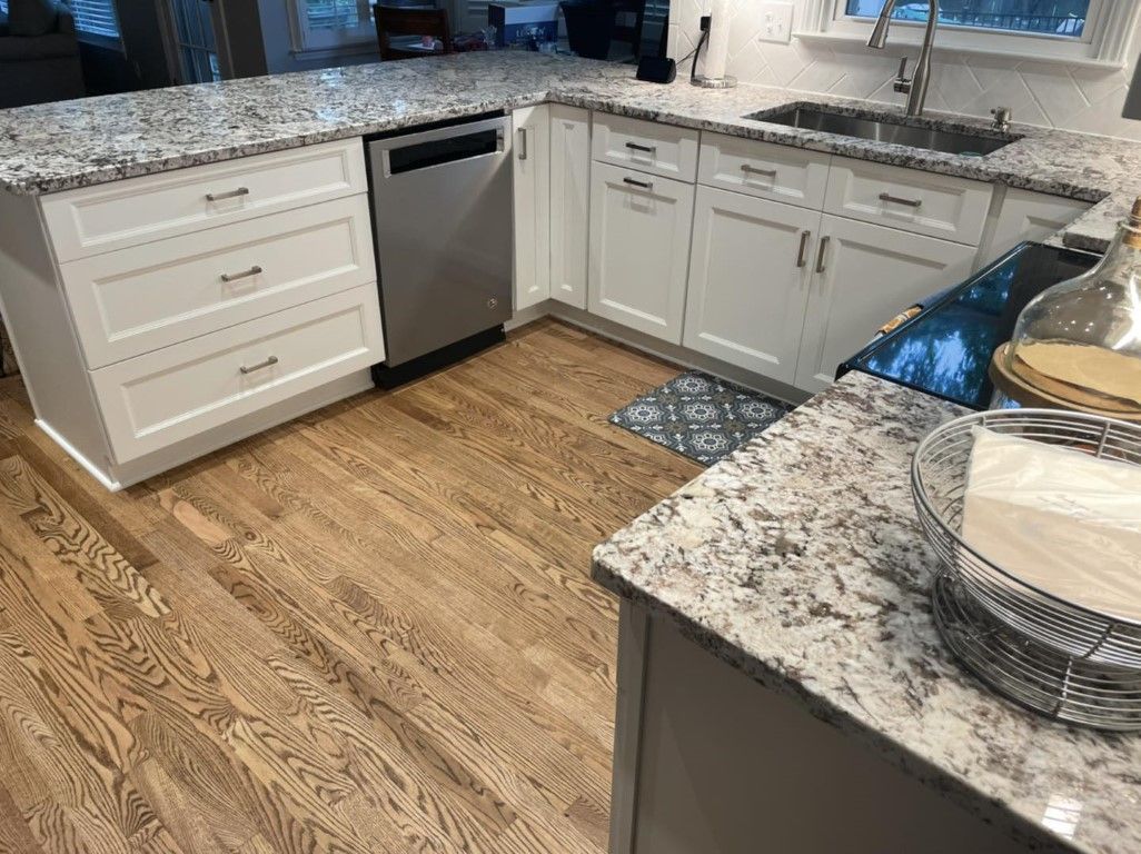 Kitchen with white cabinets, granite countertops, stainless steel appliances, and hardwood floors.