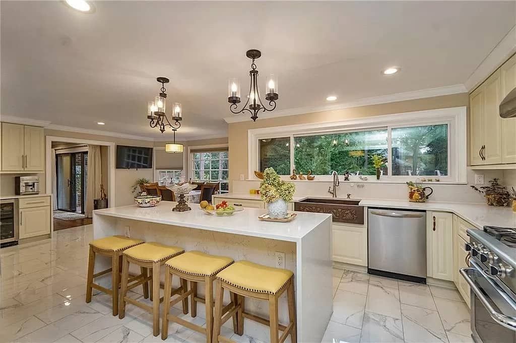 Spacious kitchen with large island, stainless steel appliances, and two chandeliers.