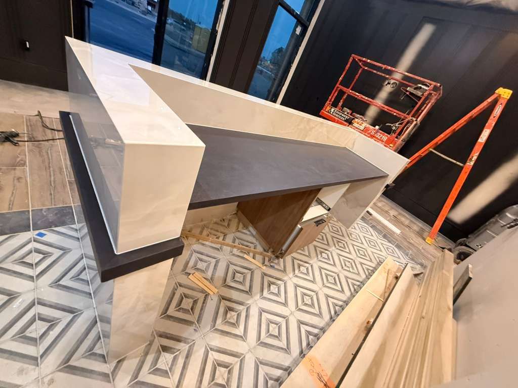 Modern, geometric counter in a space with patterned tile flooring, unfinished construction.